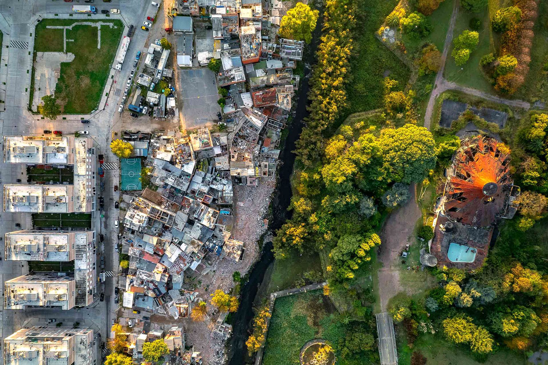 A drone photo of a slum next to a park.