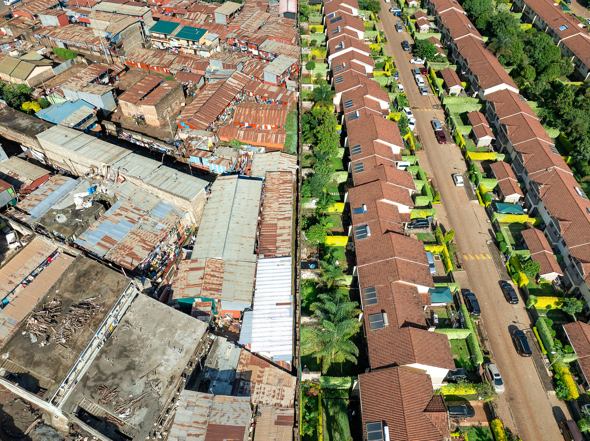 Overhead contrast between tree-shaded Nairobi mansions and adjacent high-density informal homes.
