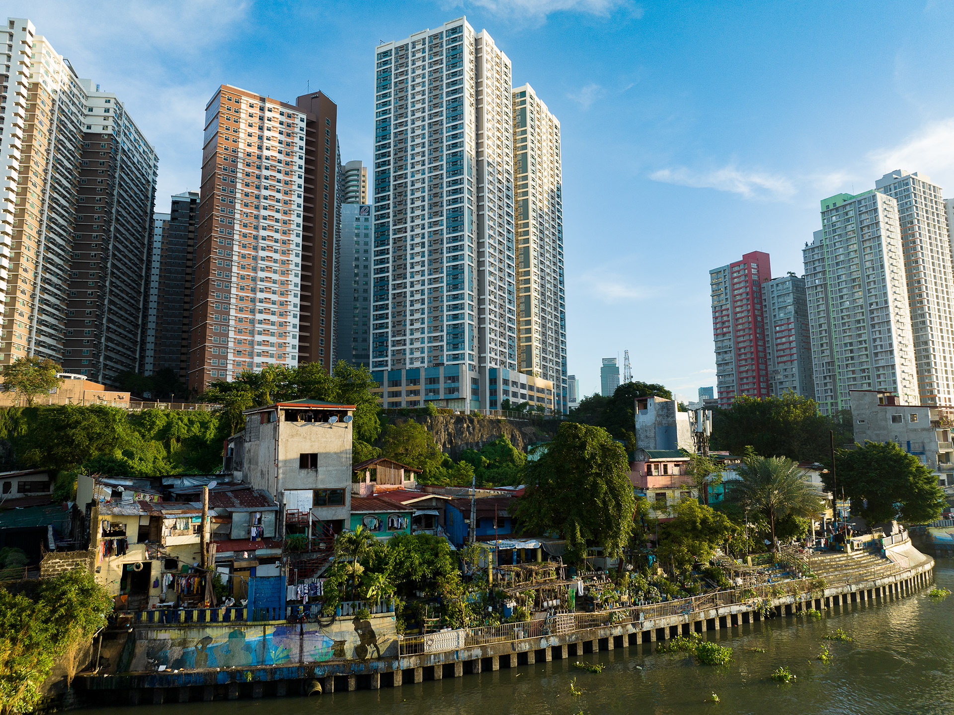 Juxtaposition of gleaming high-rise towers beside informal riverside homes.