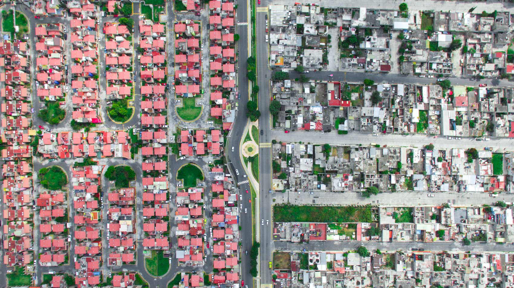 a rich community with red roofs and a poor grey community in mexico city.
