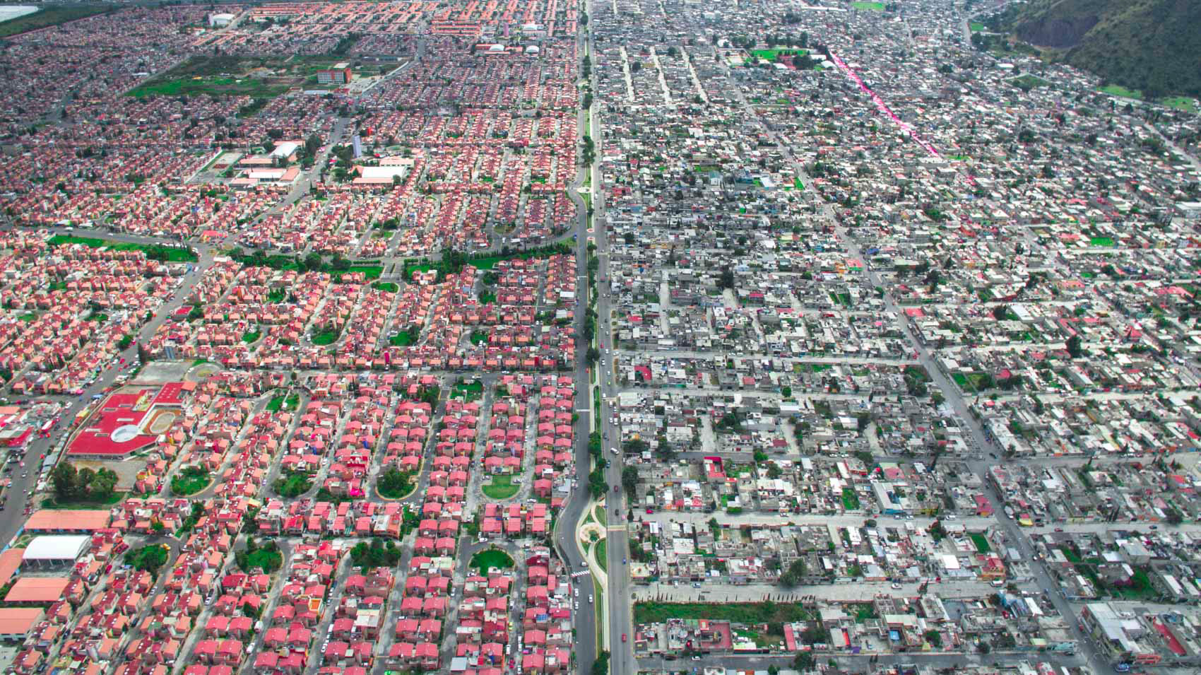 a rich community with red roofs and a poor grey community in mexico city.