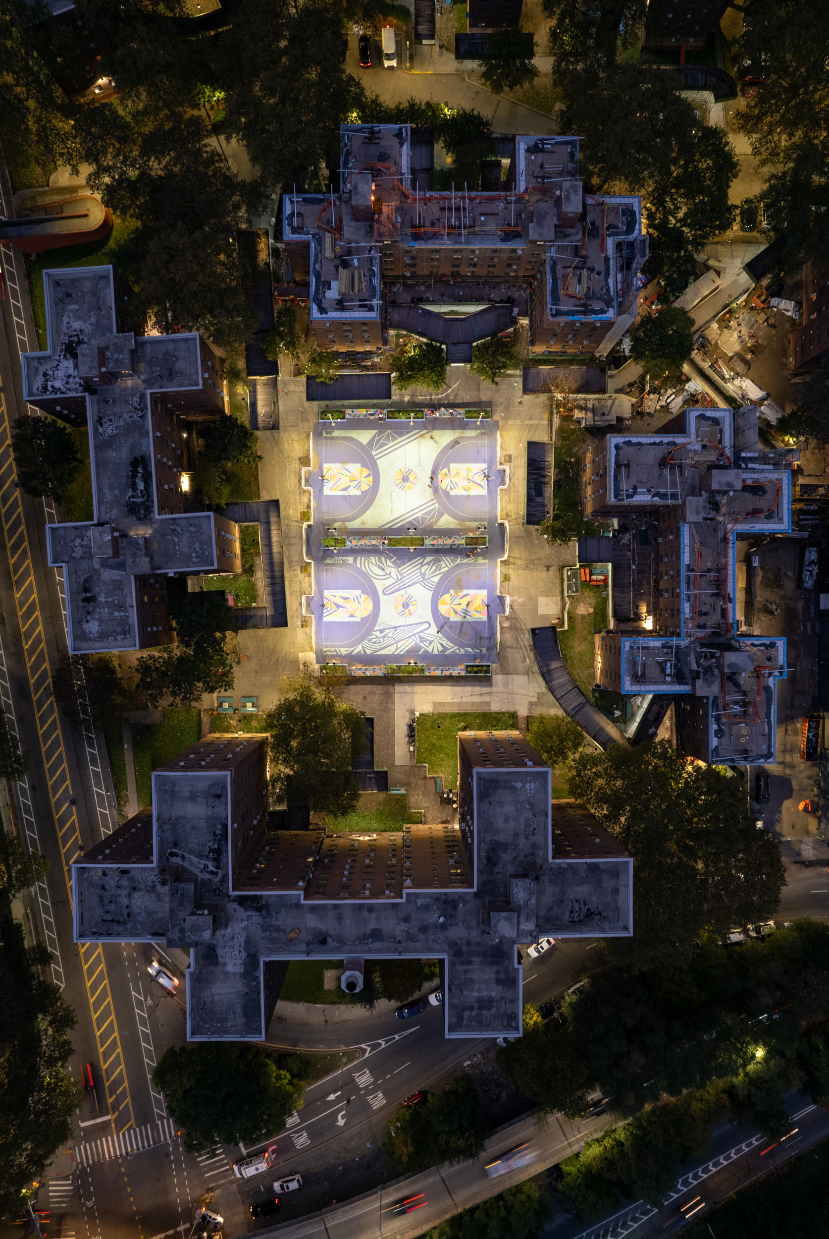 Nightime view of basketball courts and purple apartment blocks.