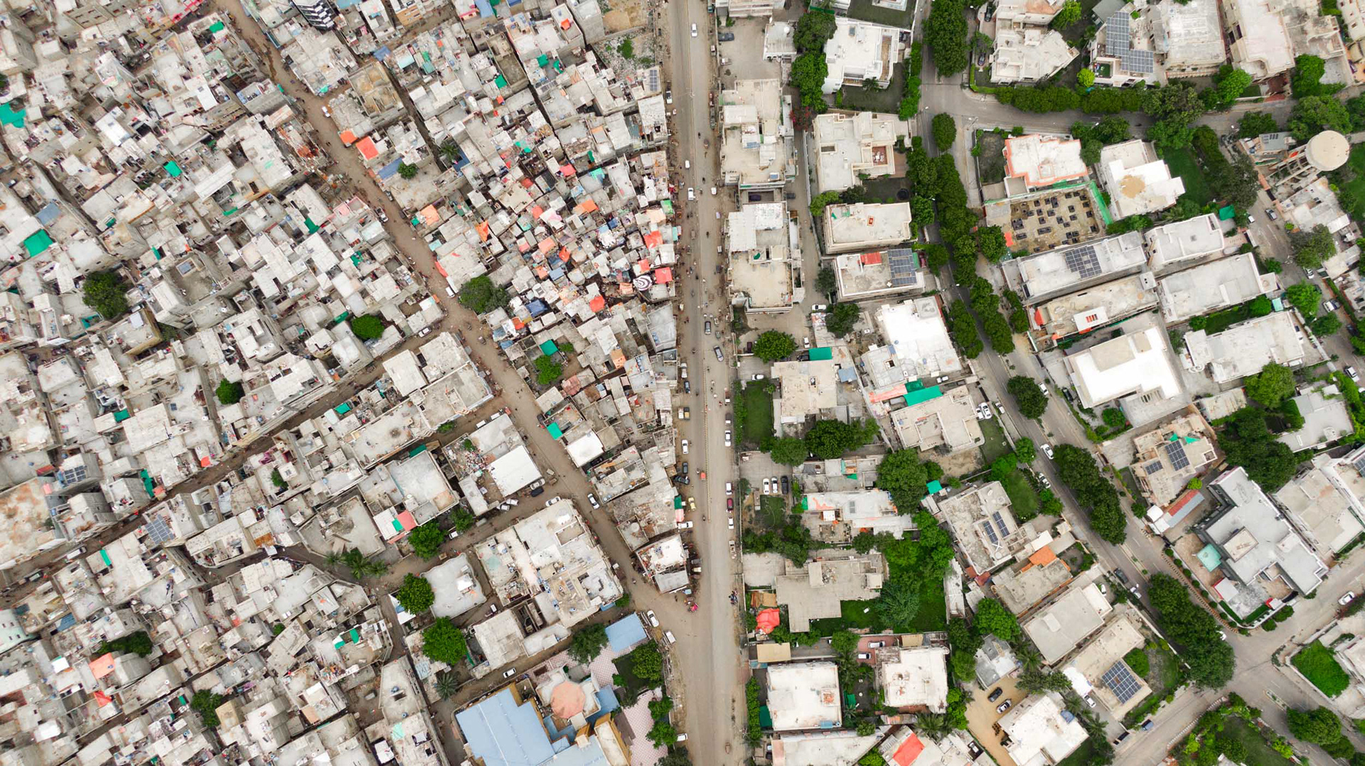 A drone view of a green leafy suburb next to a grey dense suburb.