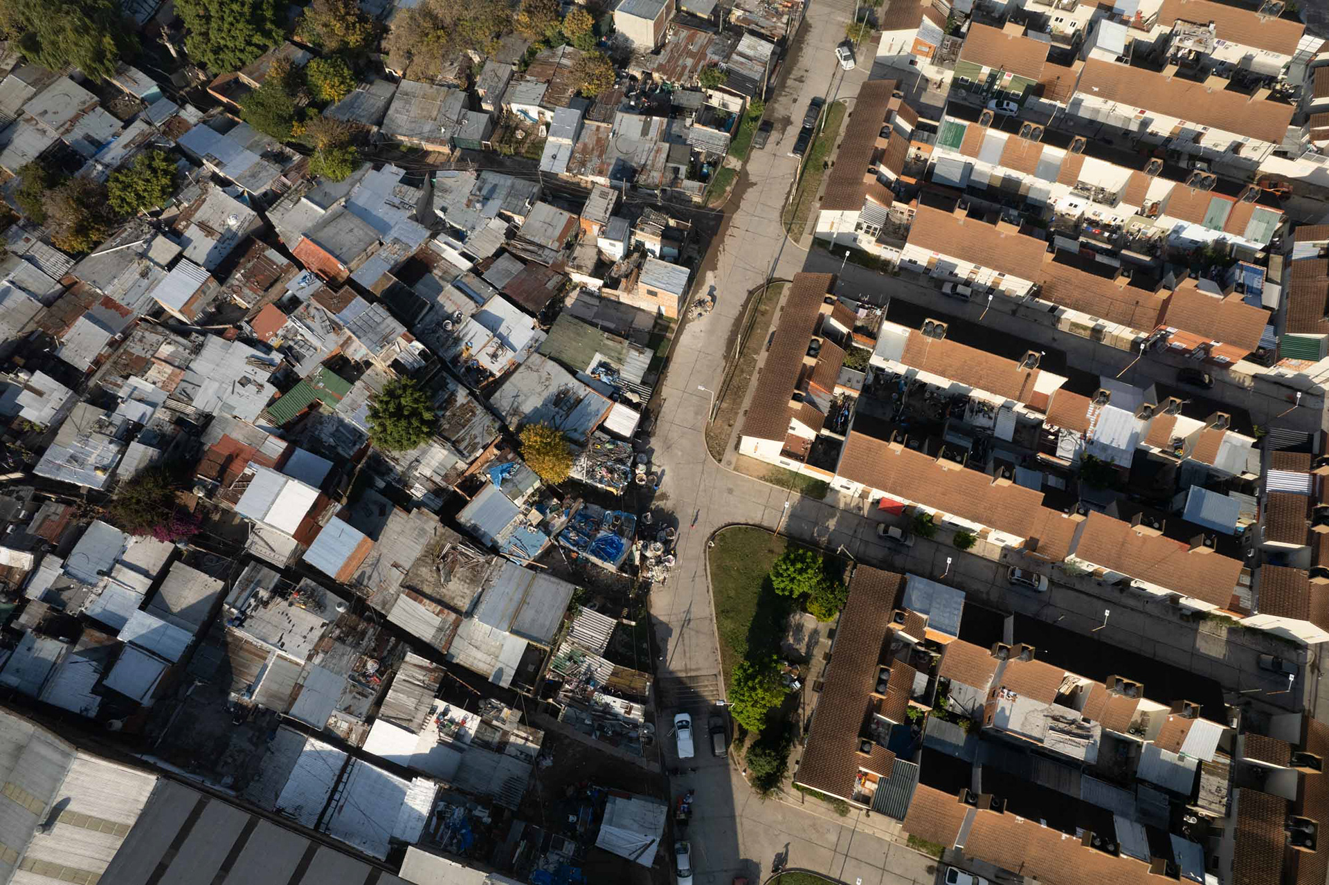 A drone photo of a slum next to brown houses.