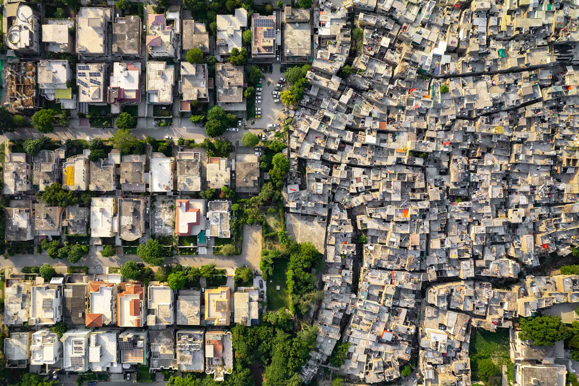 A drone view of a slum next to large houses.