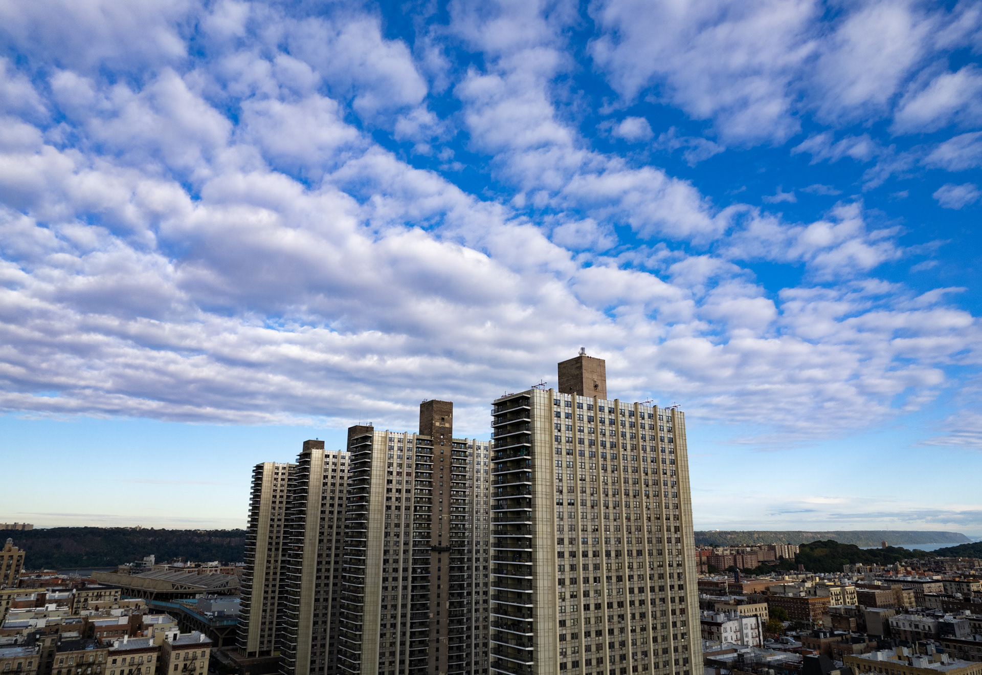A drone photo of four skyscrapers with a blue sky and clouds.
