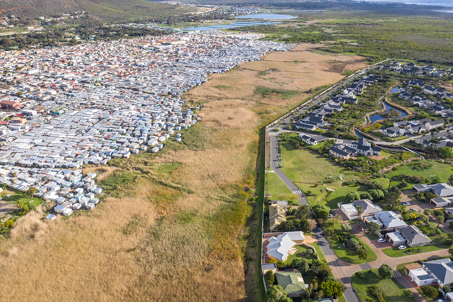 slums next to a lake with wealthy homes in cape town