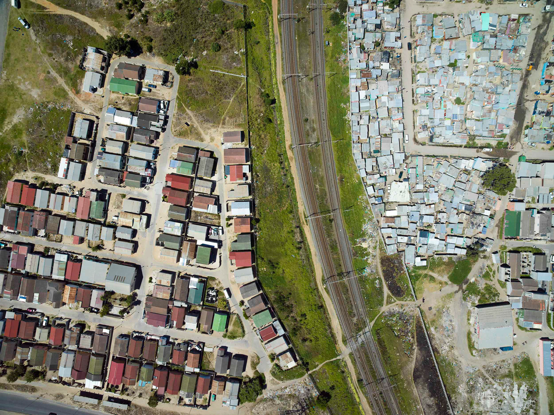 aerial view of shacks and homes and train tracks in cape town