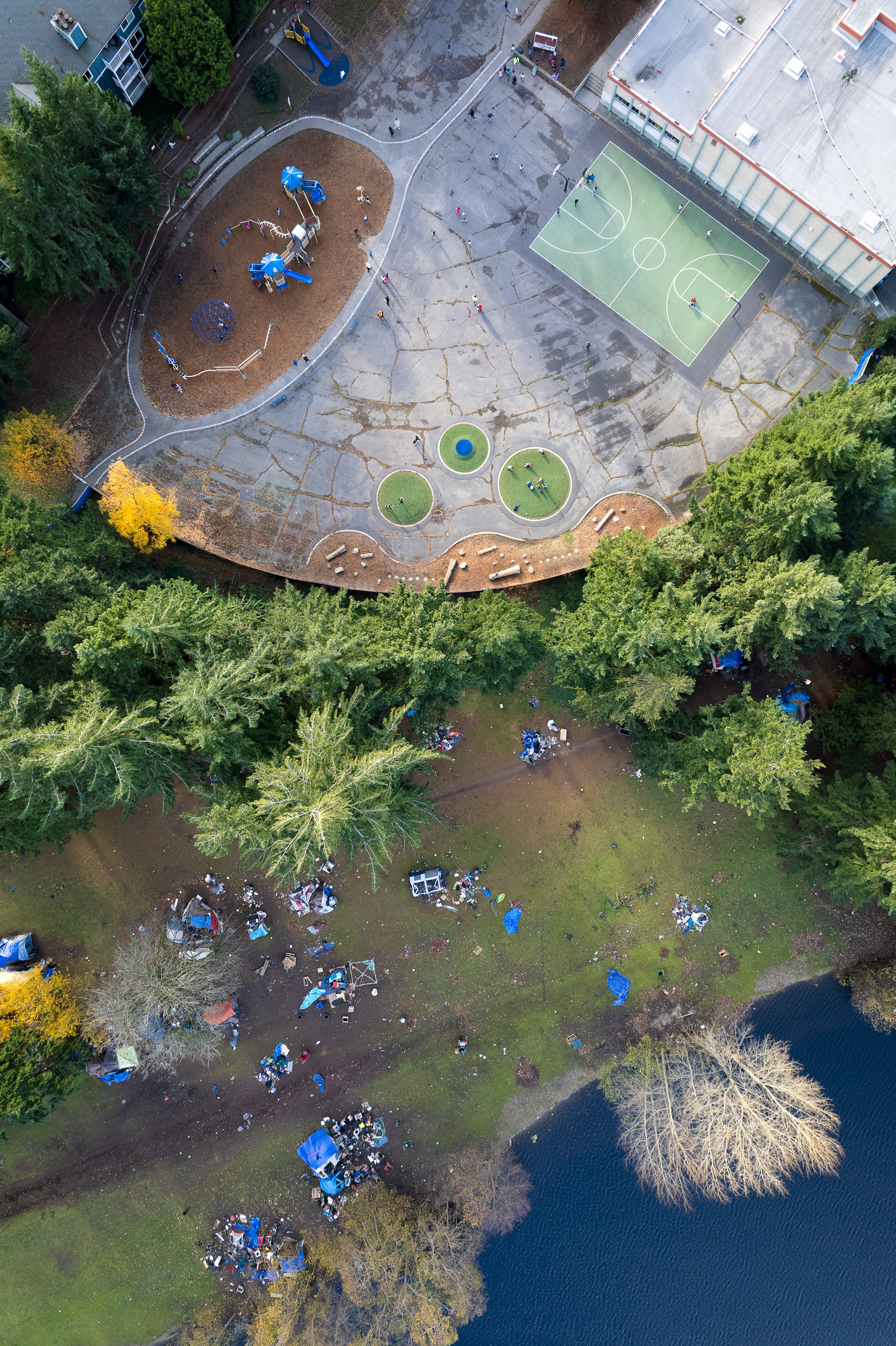 aerial view of a homeless camp next to a school playground with children in seattle