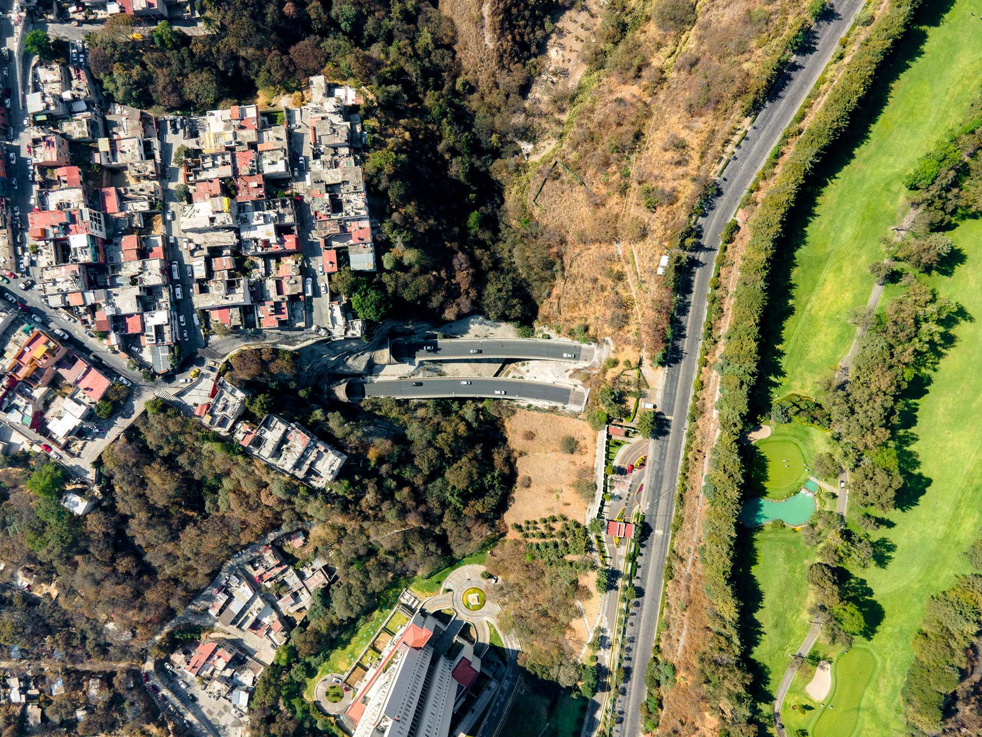golf course with rich homes next to slums in mexico city with highway