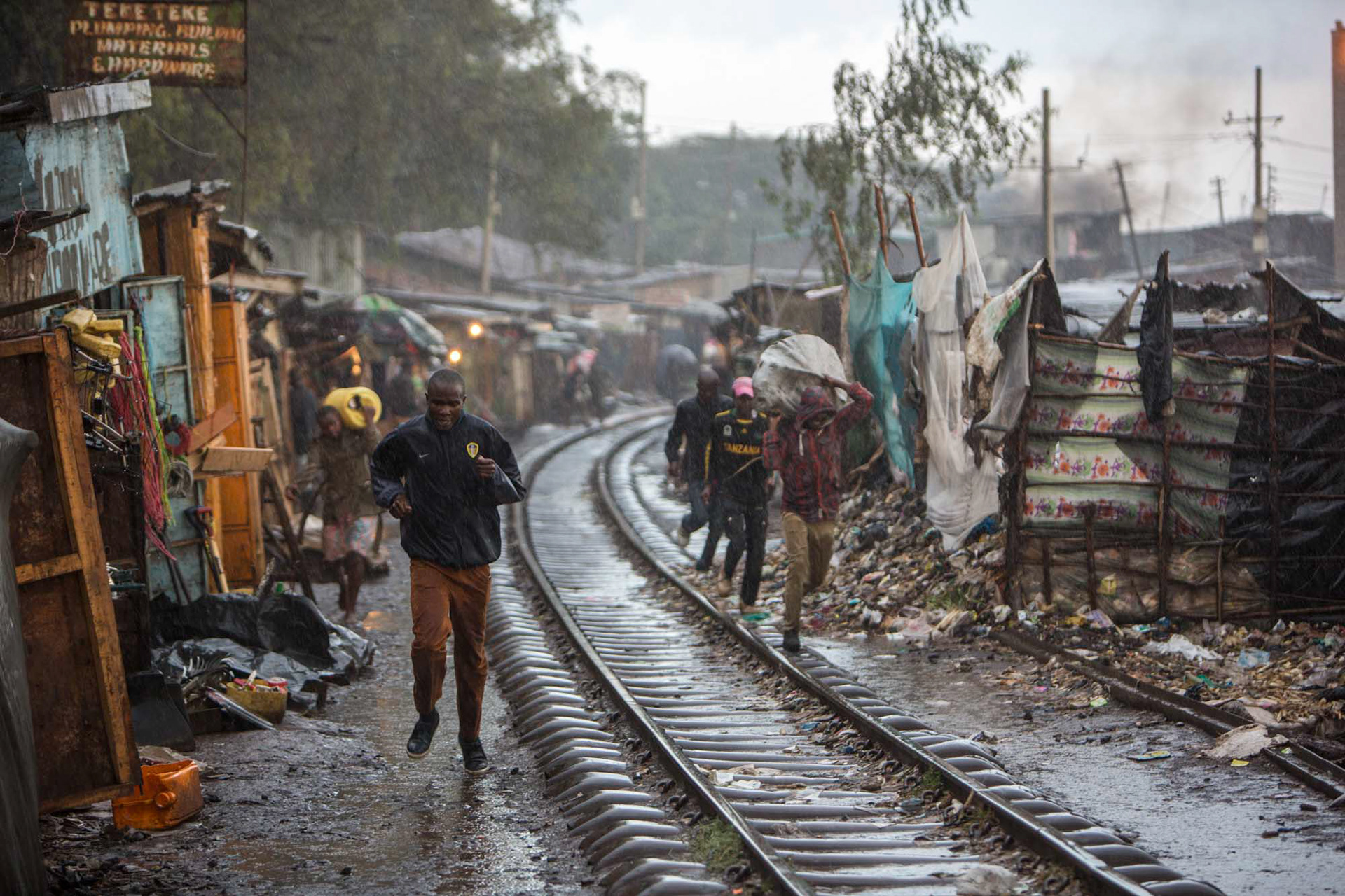 men run on train tracks in the rain