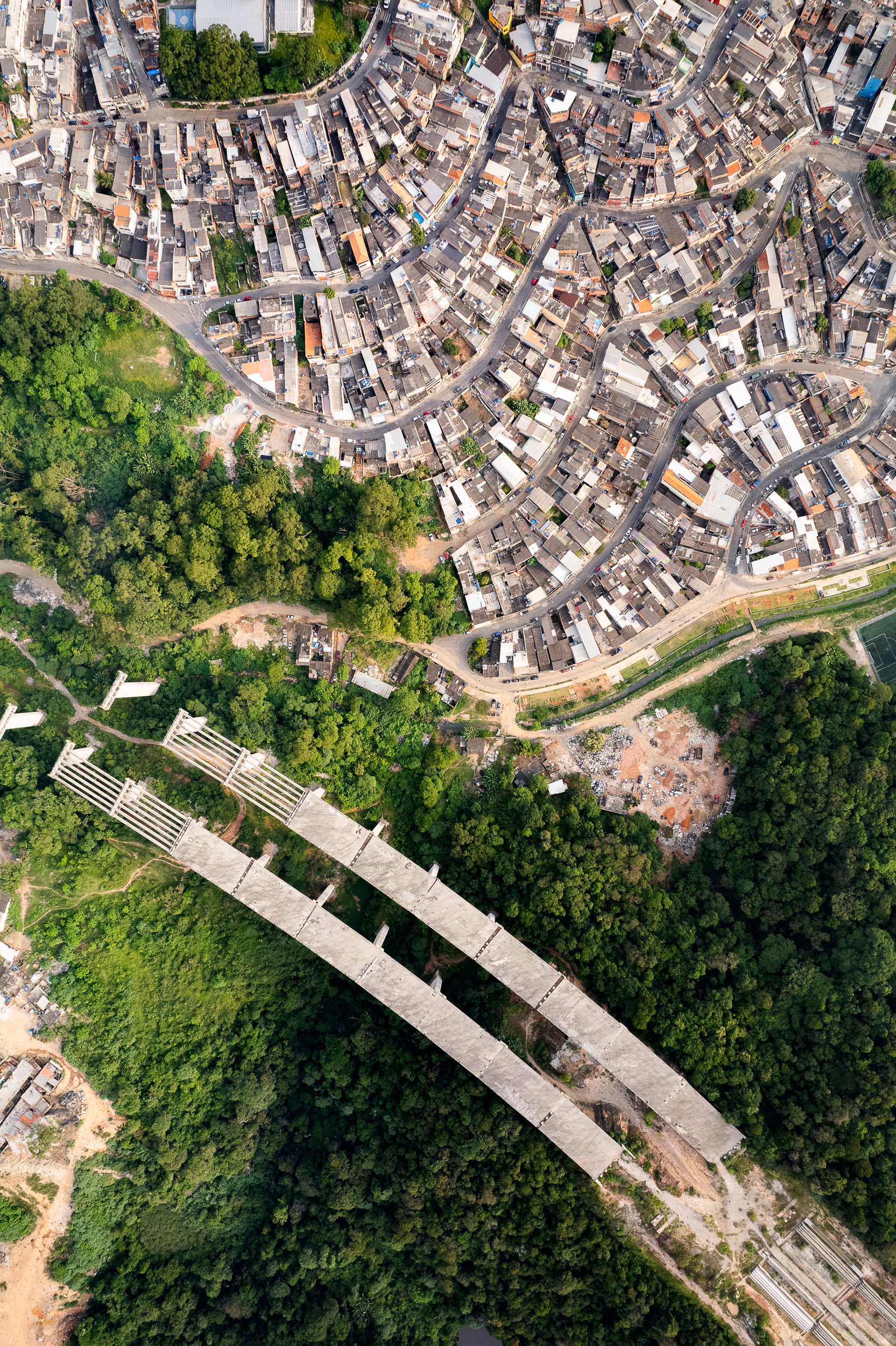 São Paulo’s Rodoanel highway cuts through dense forest and skirts a favela on the edge of Brasilândia, a physical boundary reinforcing social marginalization.
