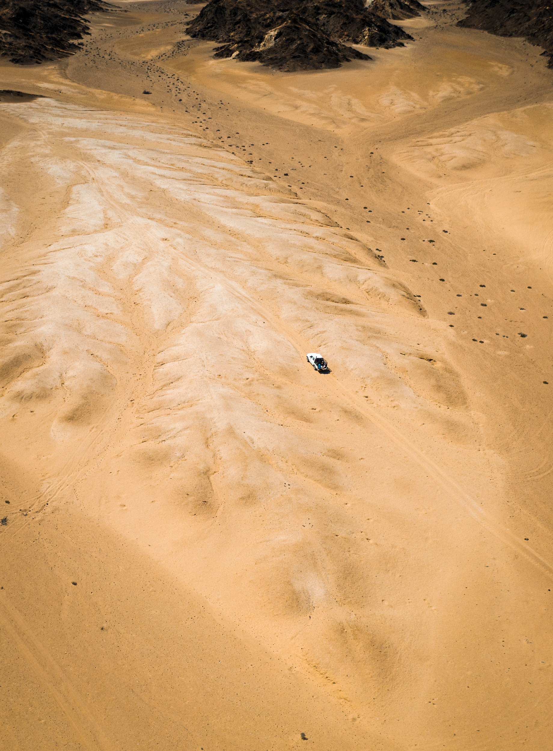 aerial view of jeep driving in sand dunes
