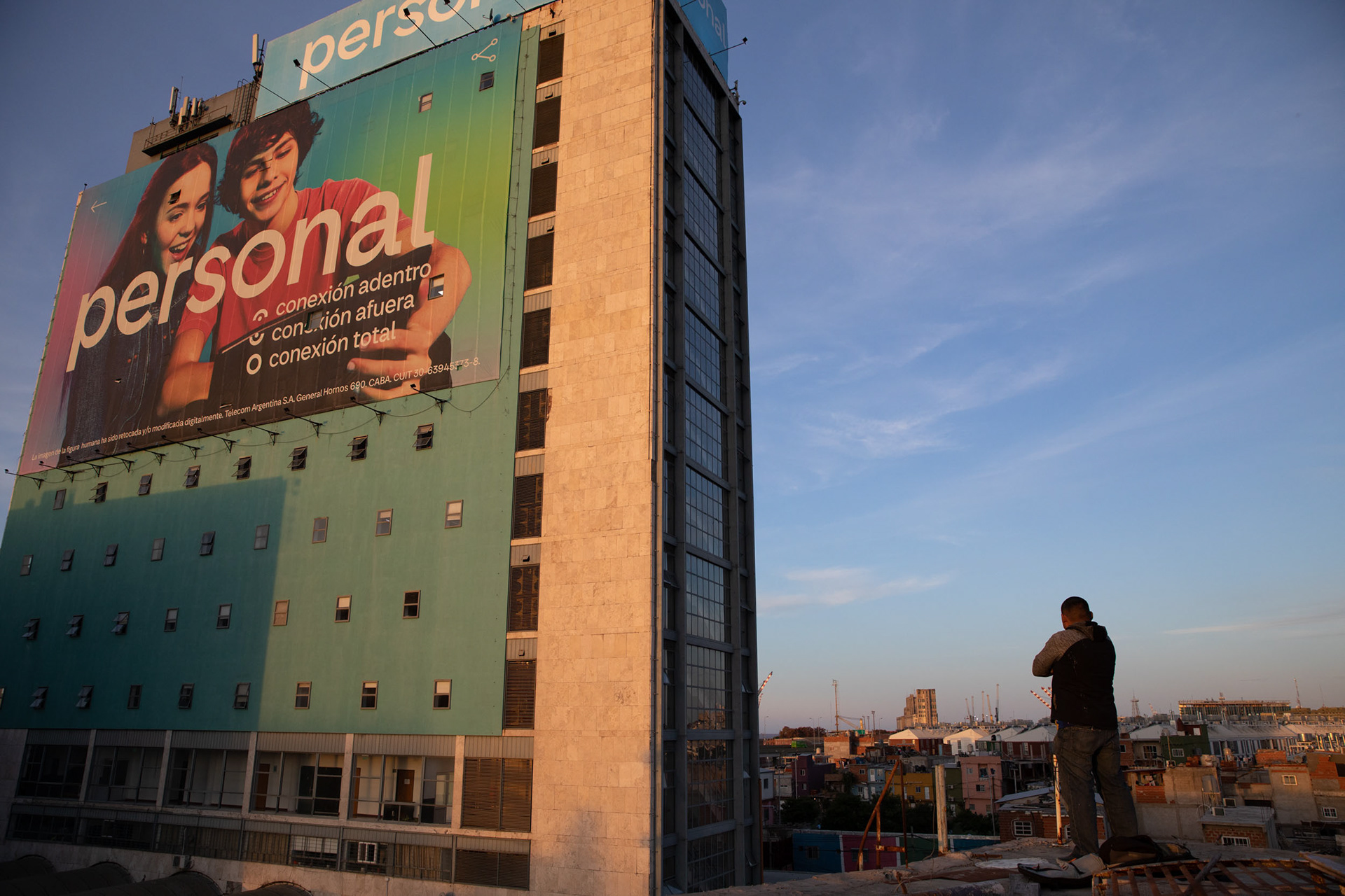 A man standing on a roof looking at a building.