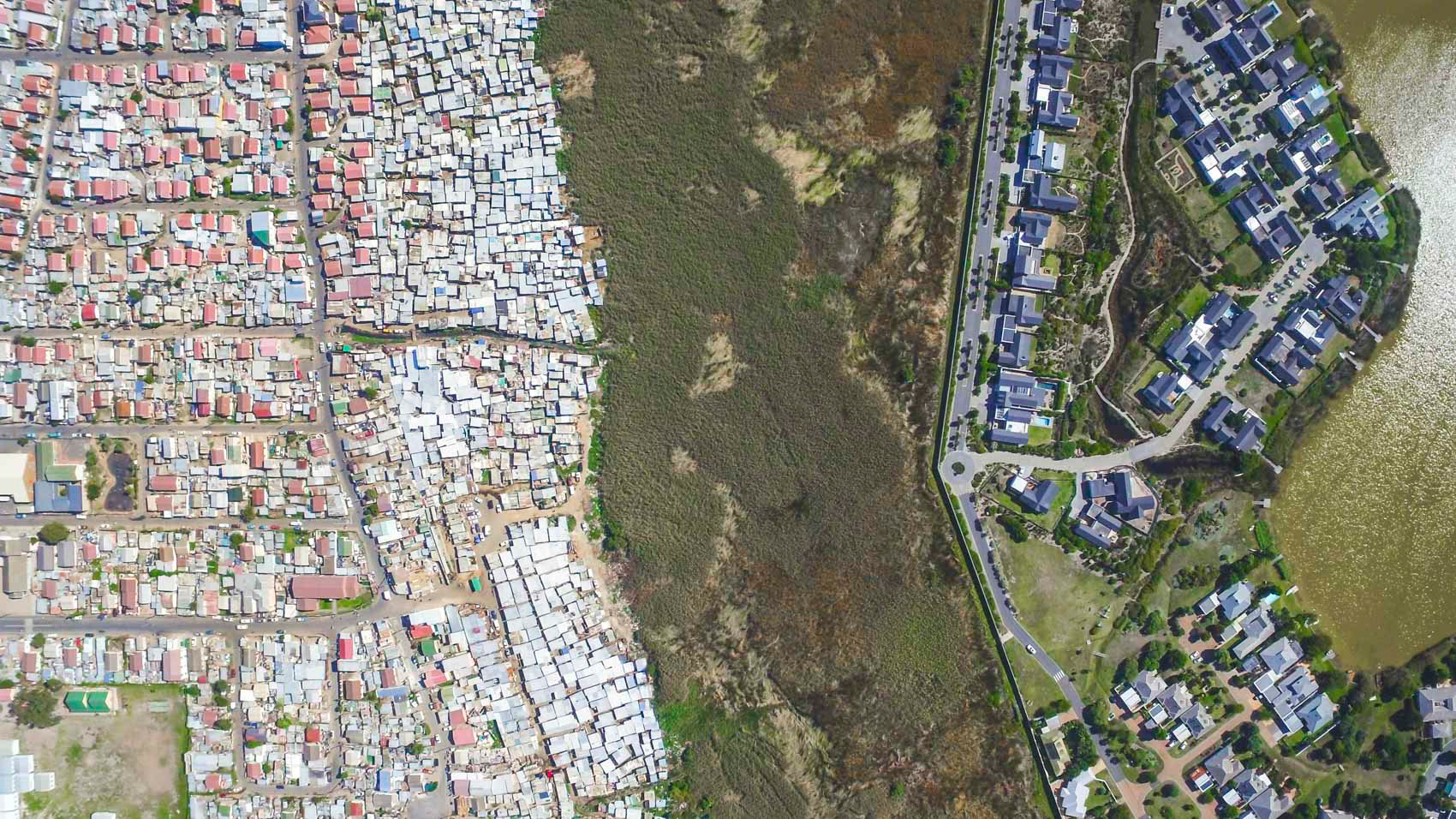 slums next to a lake with wealthy homes in cape town