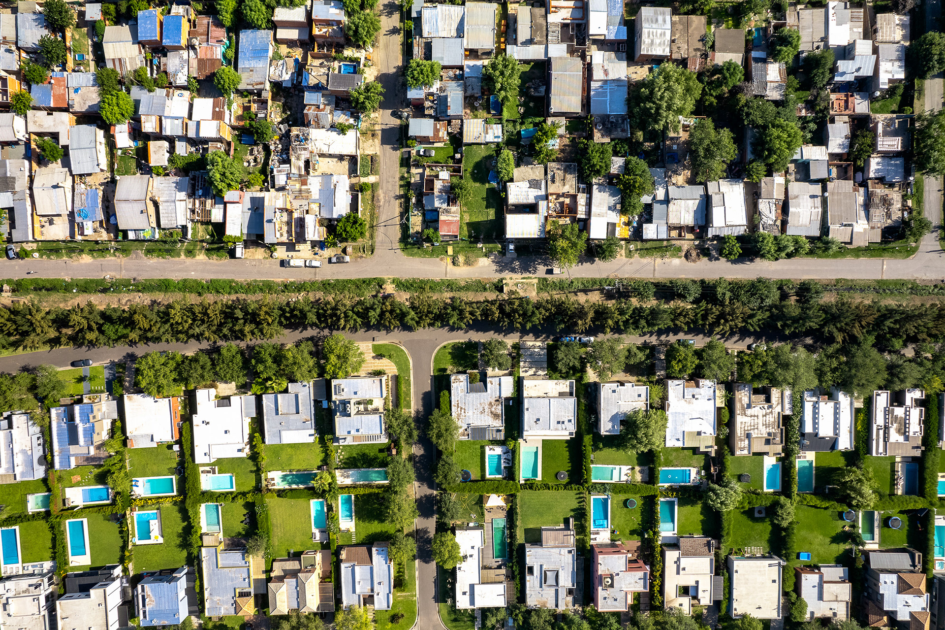 A drone photo of homes with swimming pools next to a community.