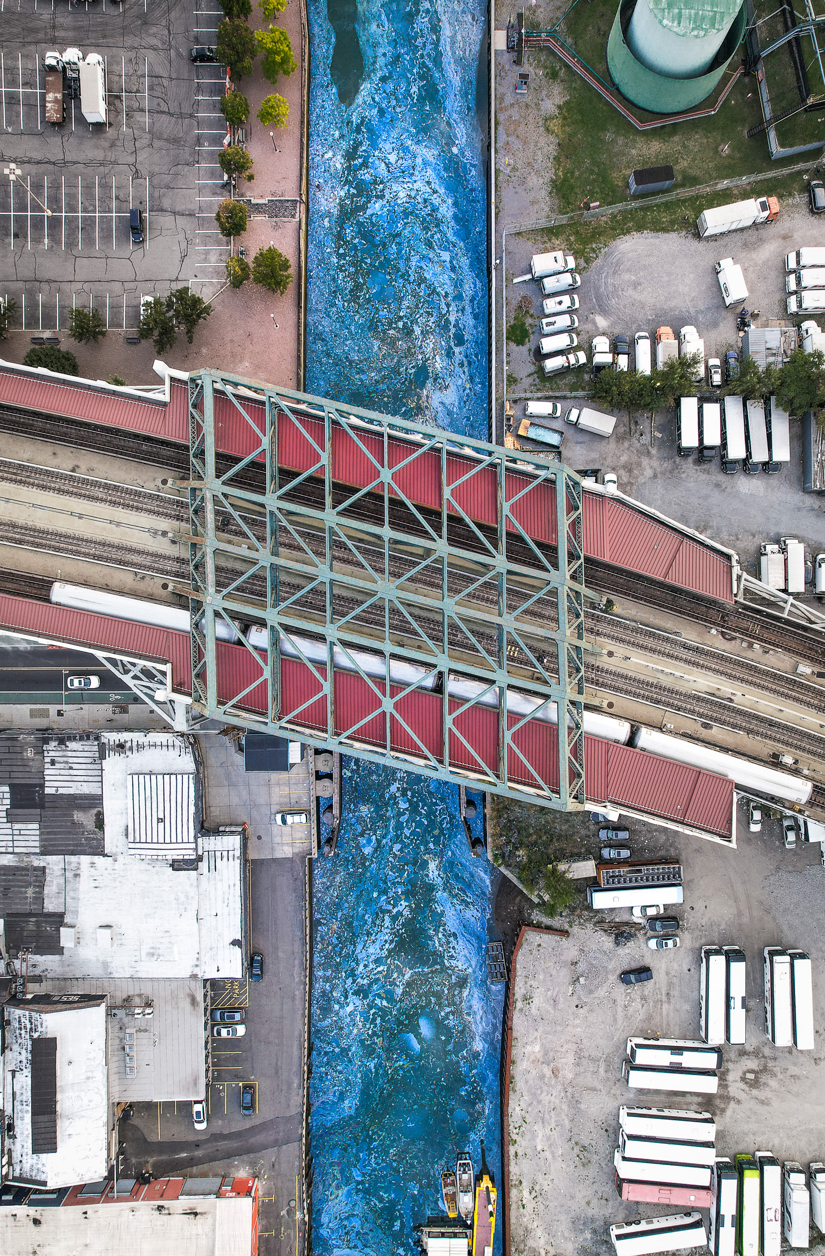 A drone photo of a bridge with a subway train over a polluted river.
