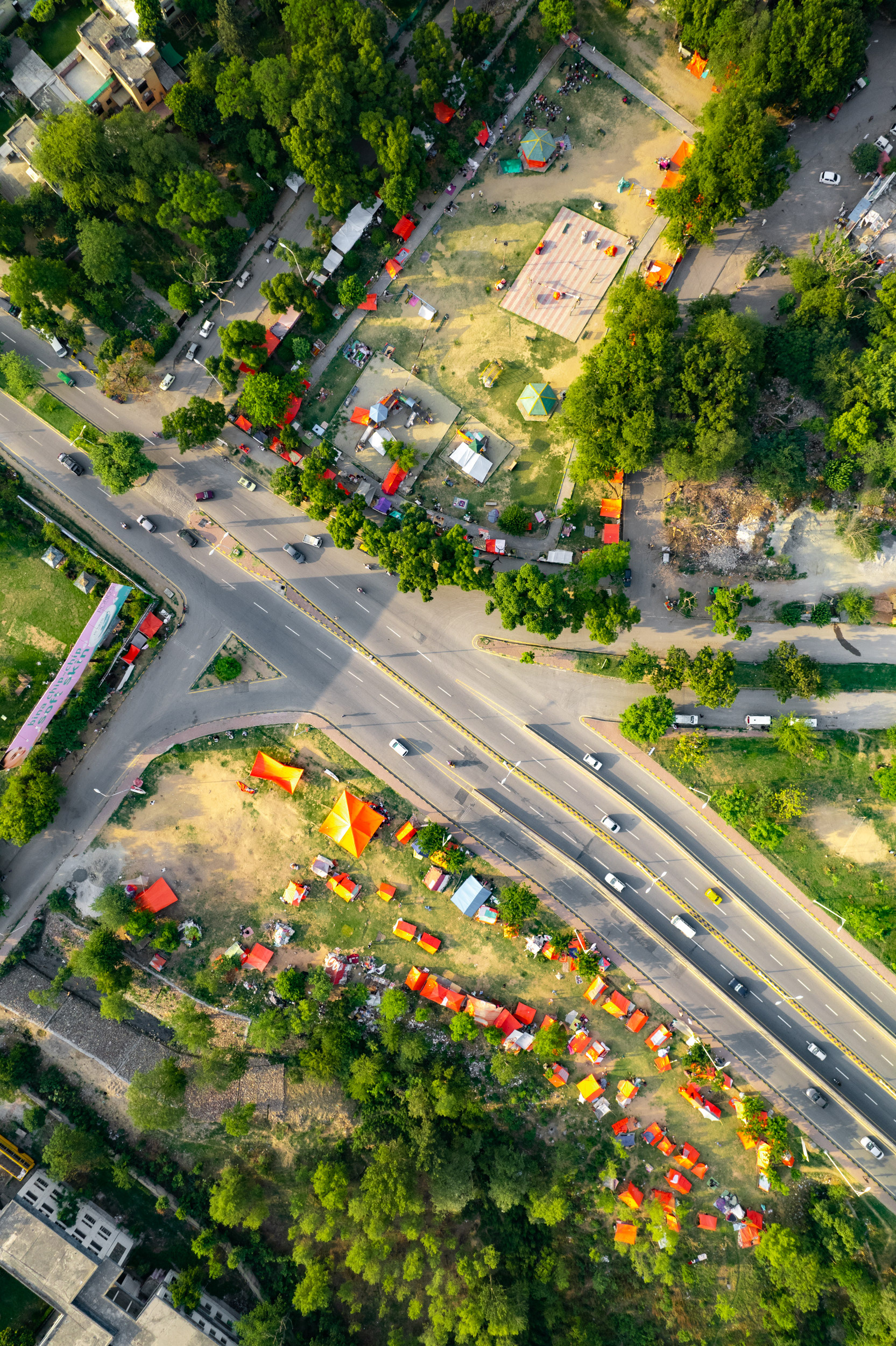 A drone view of a green neighborhood with red tents.