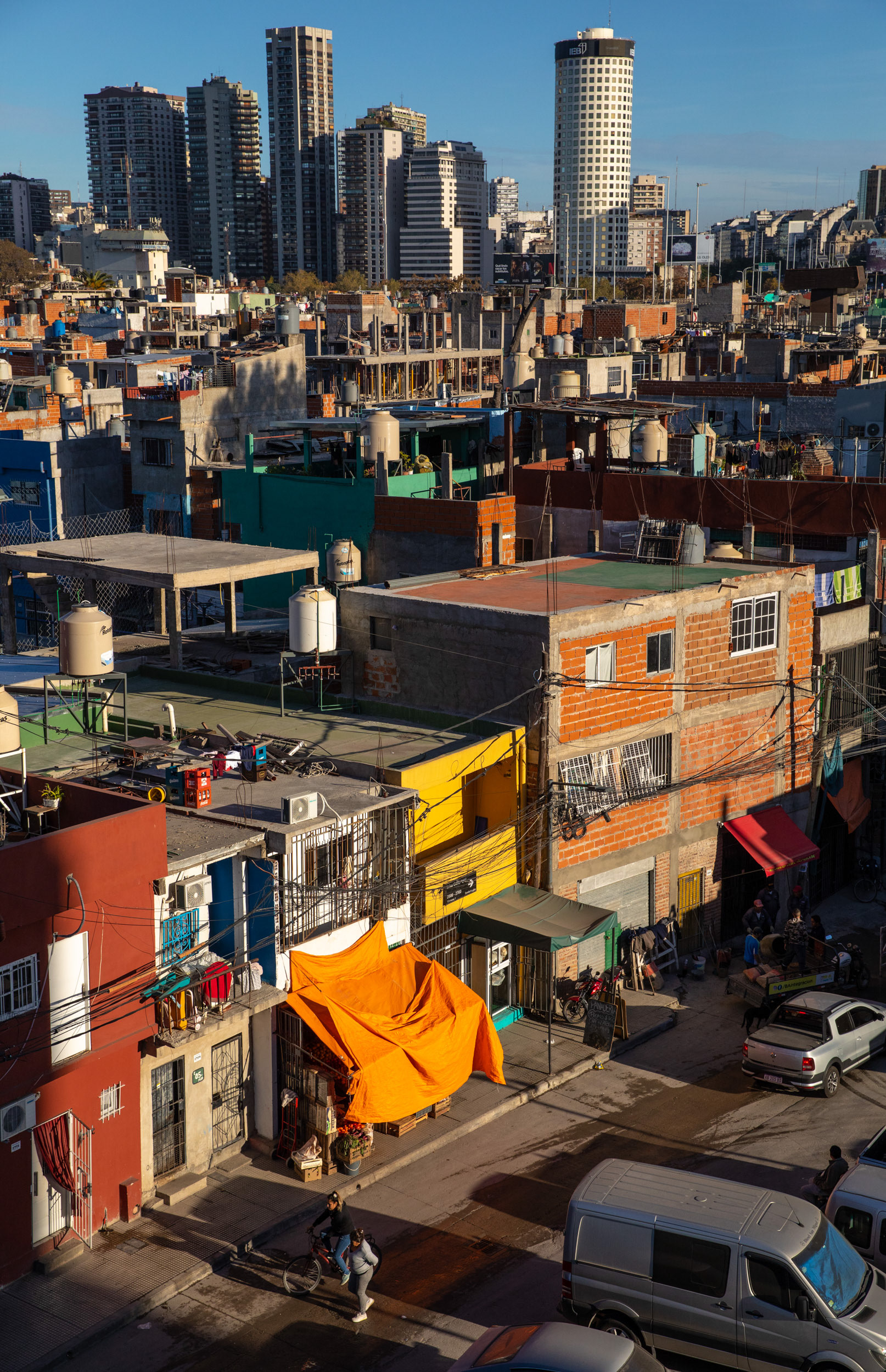 Orange brick buildings in a slum looking across to skyscrapers.