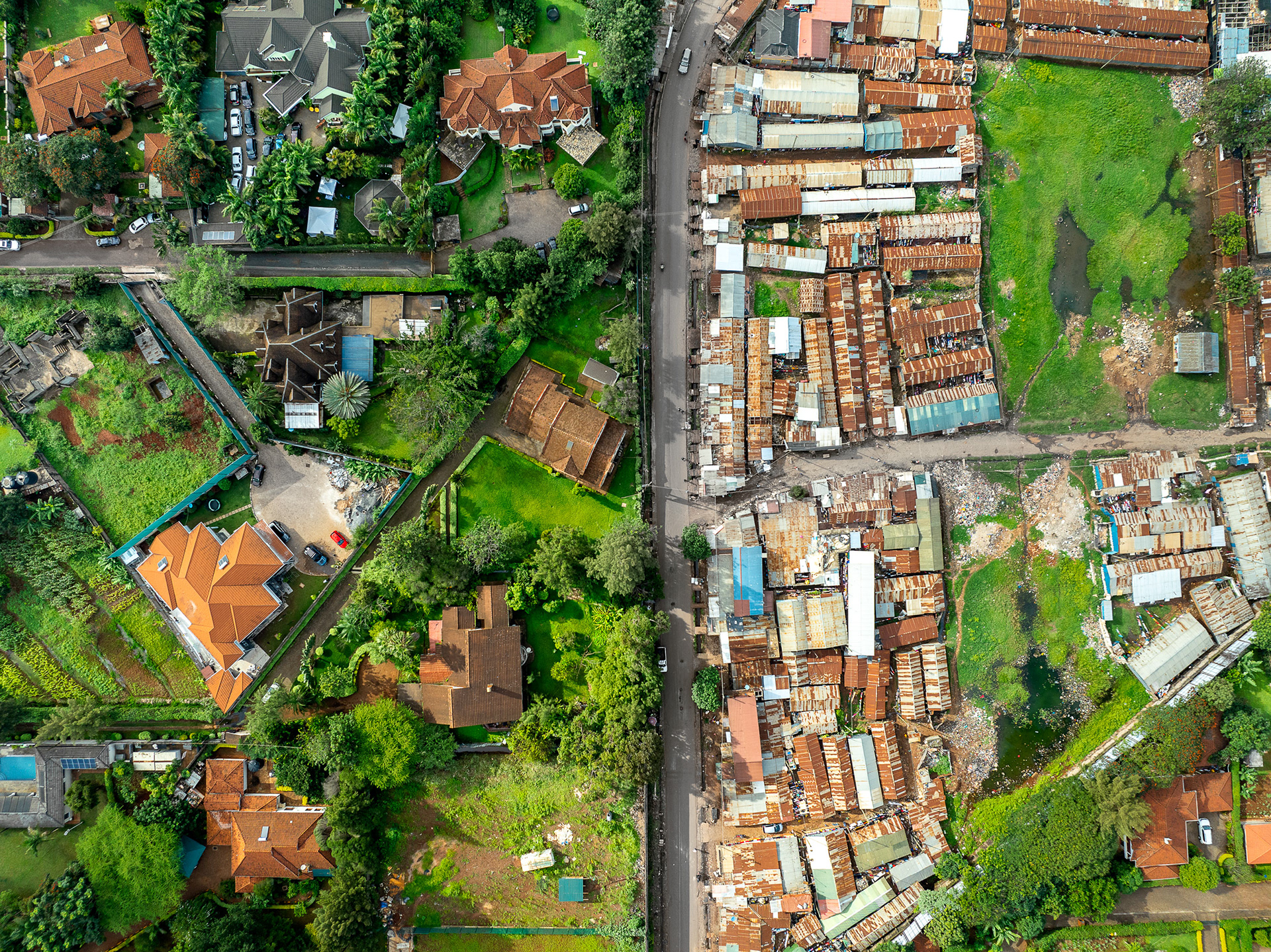 Overhead contrast between tree-shaded Nairobi mansions and adjacent high-density informal homes.