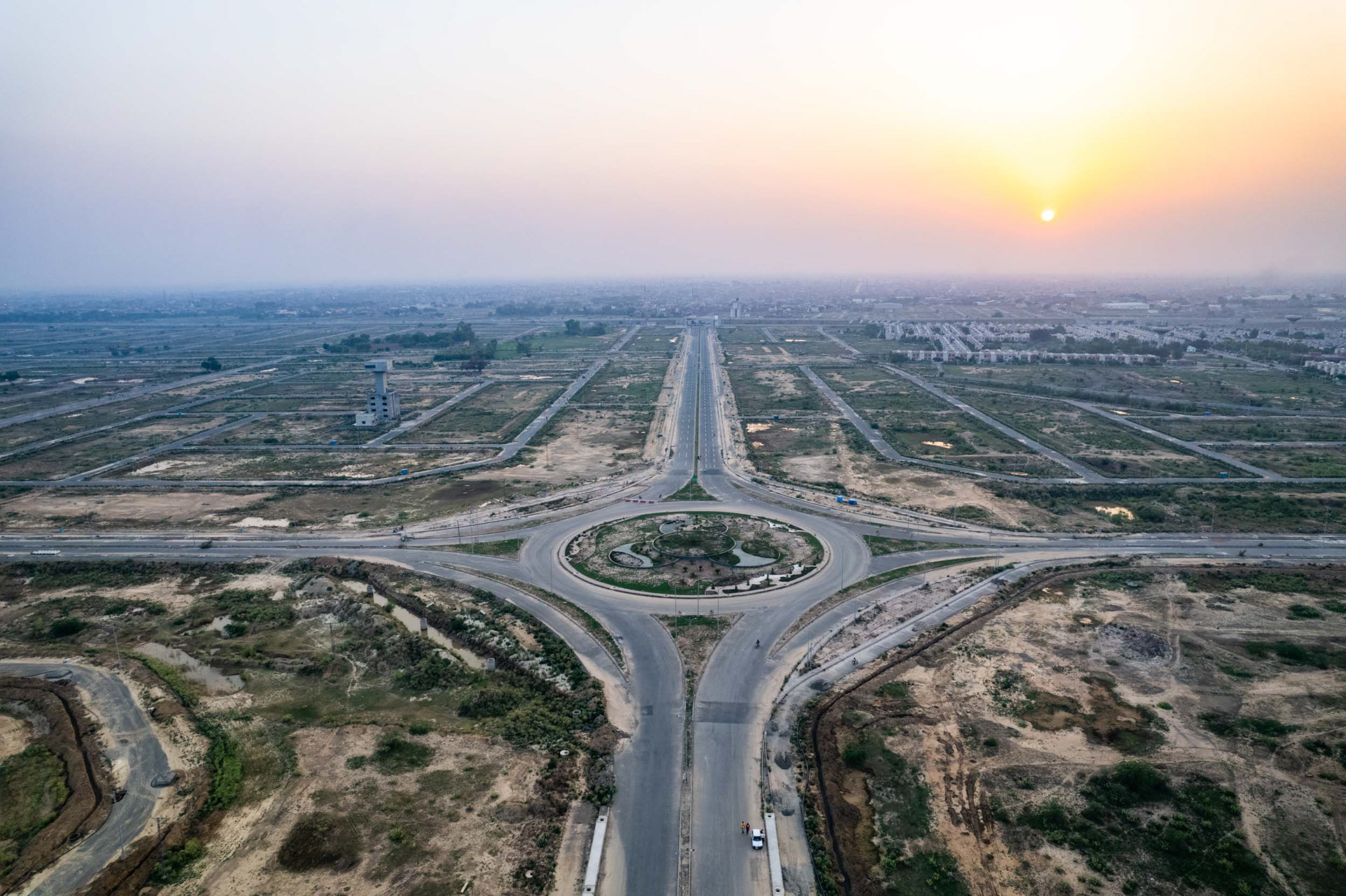 A drone view of a roundabout in an empty housing development with the setting sun.