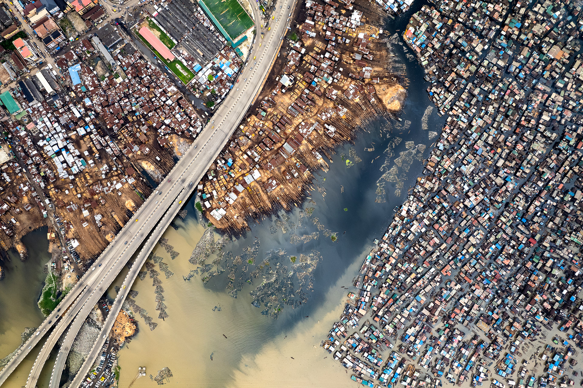 A drone view of a bridge bisecting a slum.