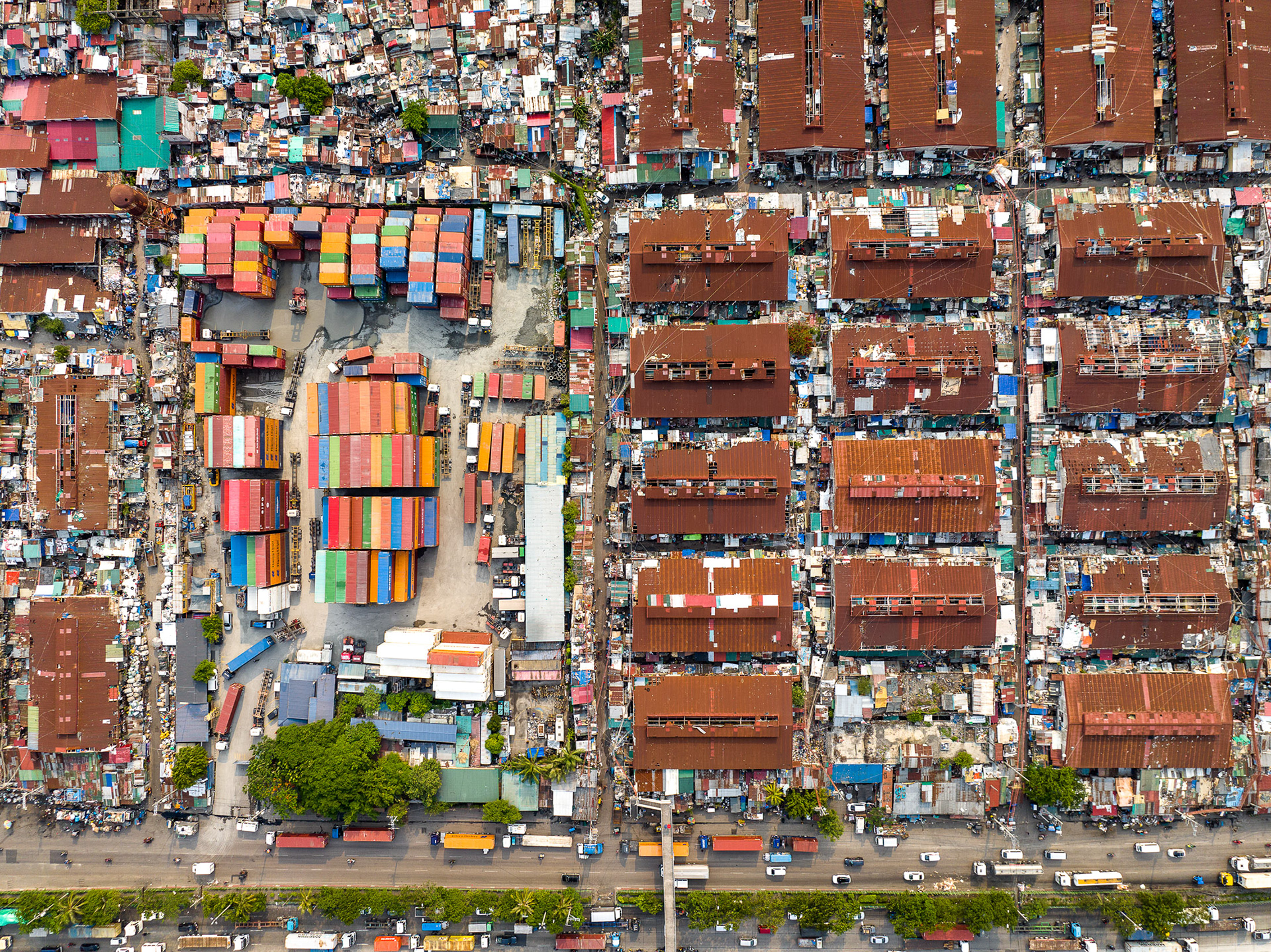Tightly packed informal housing and cargo containers form a dense, orderly grid near Manila’s port, illustrating extreme spatial congestion.