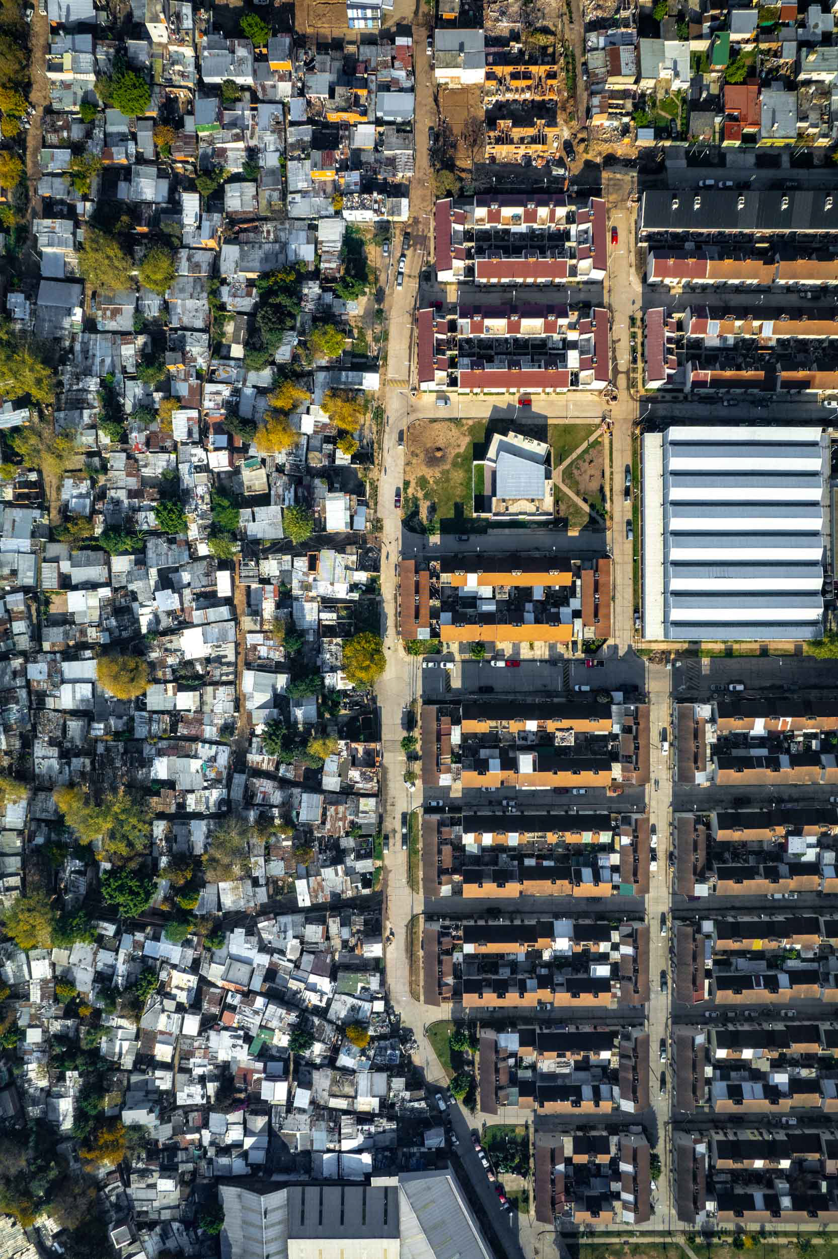 A drone photo of a slum next to brown houses.