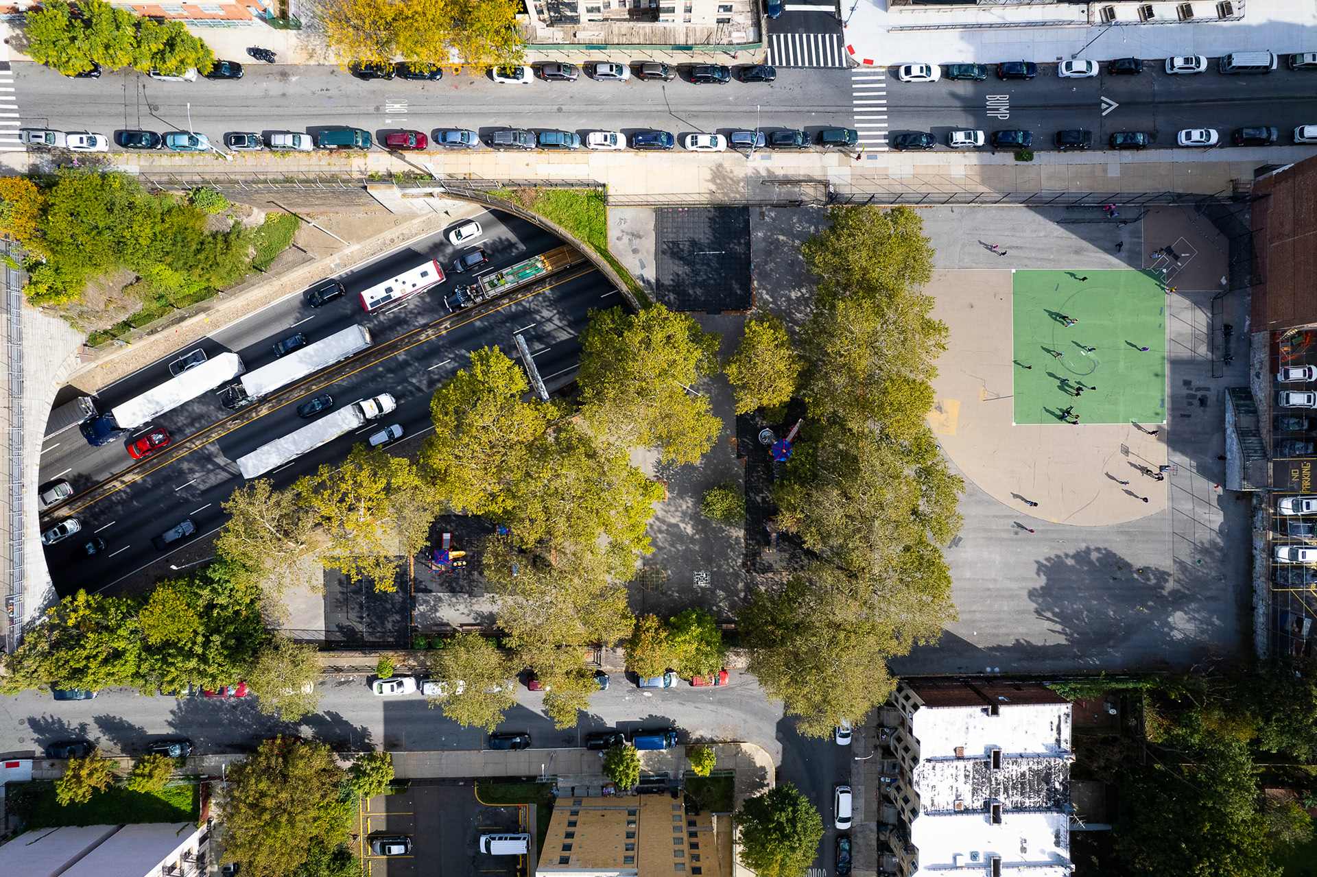 A drone photo of a highway running past a schoolyard filled with children.