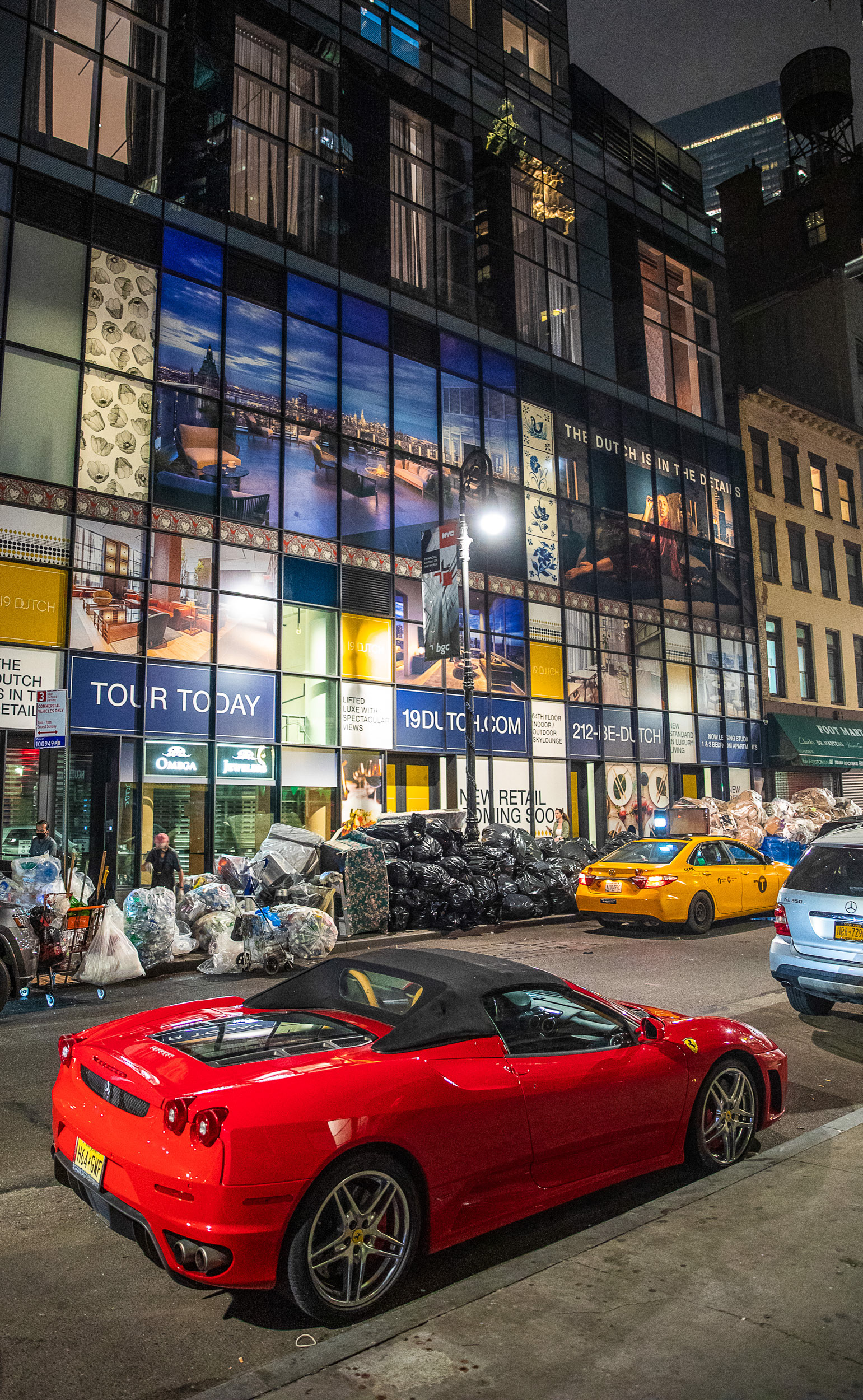 A red sportscar in front of mounds of trash.