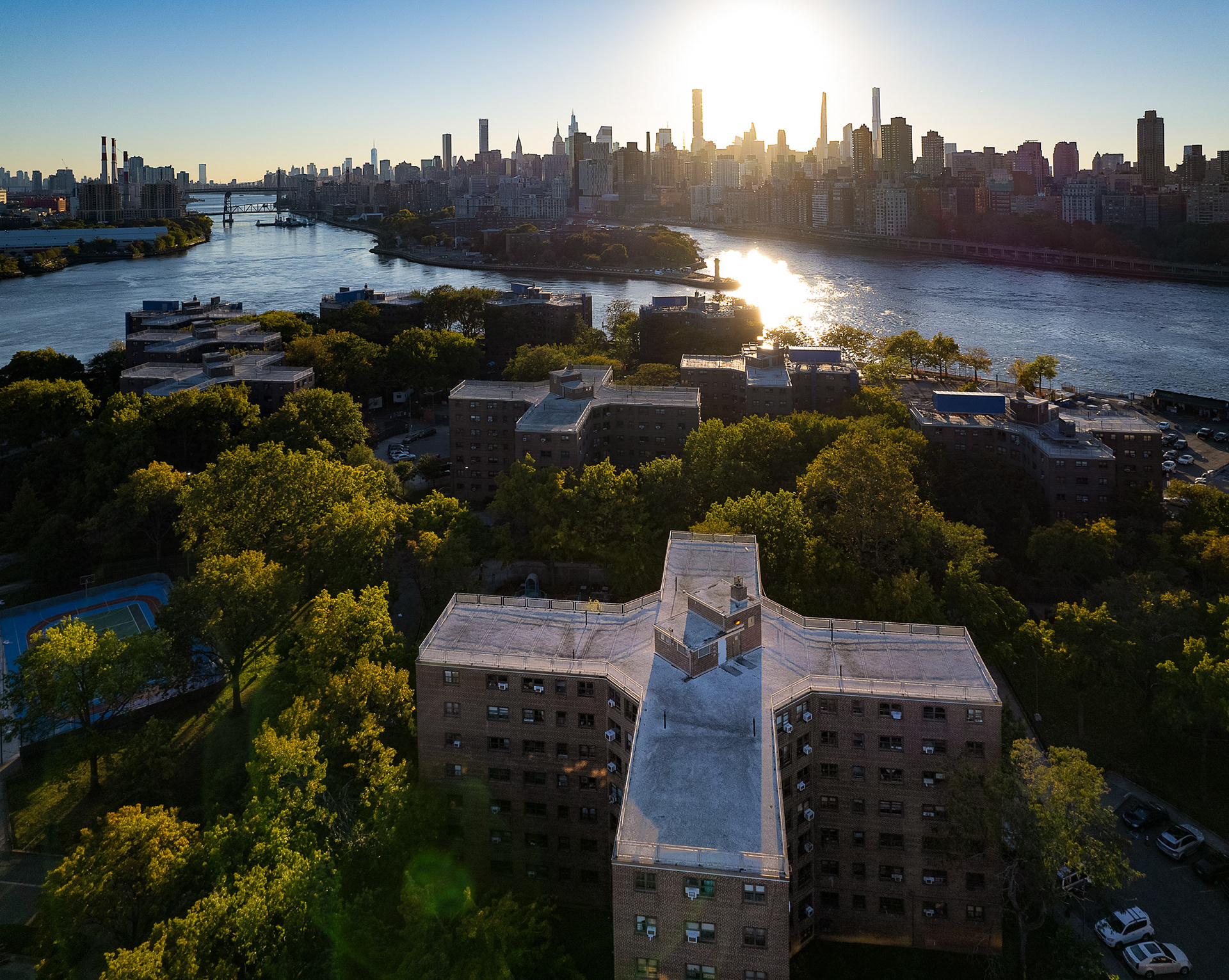 A drone photo of a cross-like building and a river with skyscrapers in the background.