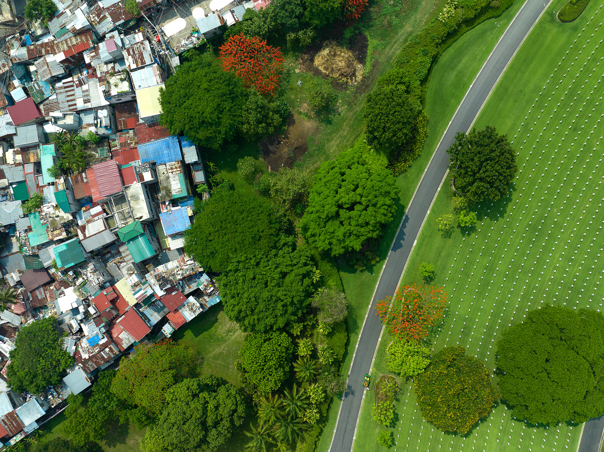 Overhead image of a low-income neighborhood in Metro Manila nestled between the Manila American Cemetery and Bonifacio Global City, highlighting stark urban inequality.