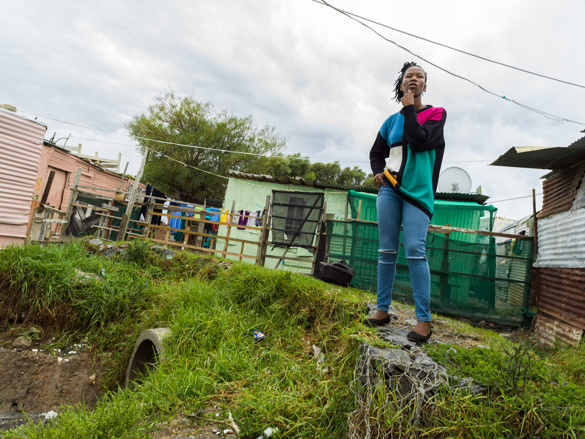 woman standing among shacks in cape town south africa