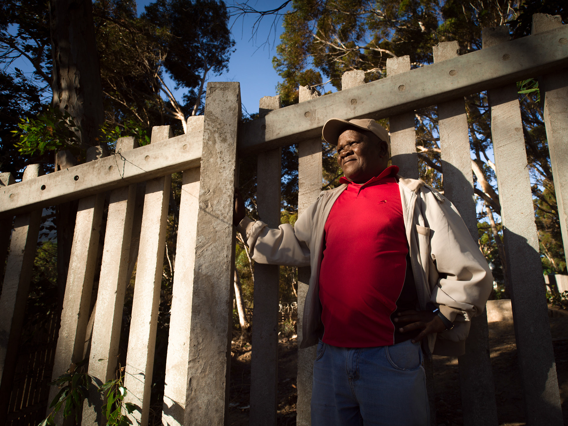 man standing along fence in a slum in cape town south africa