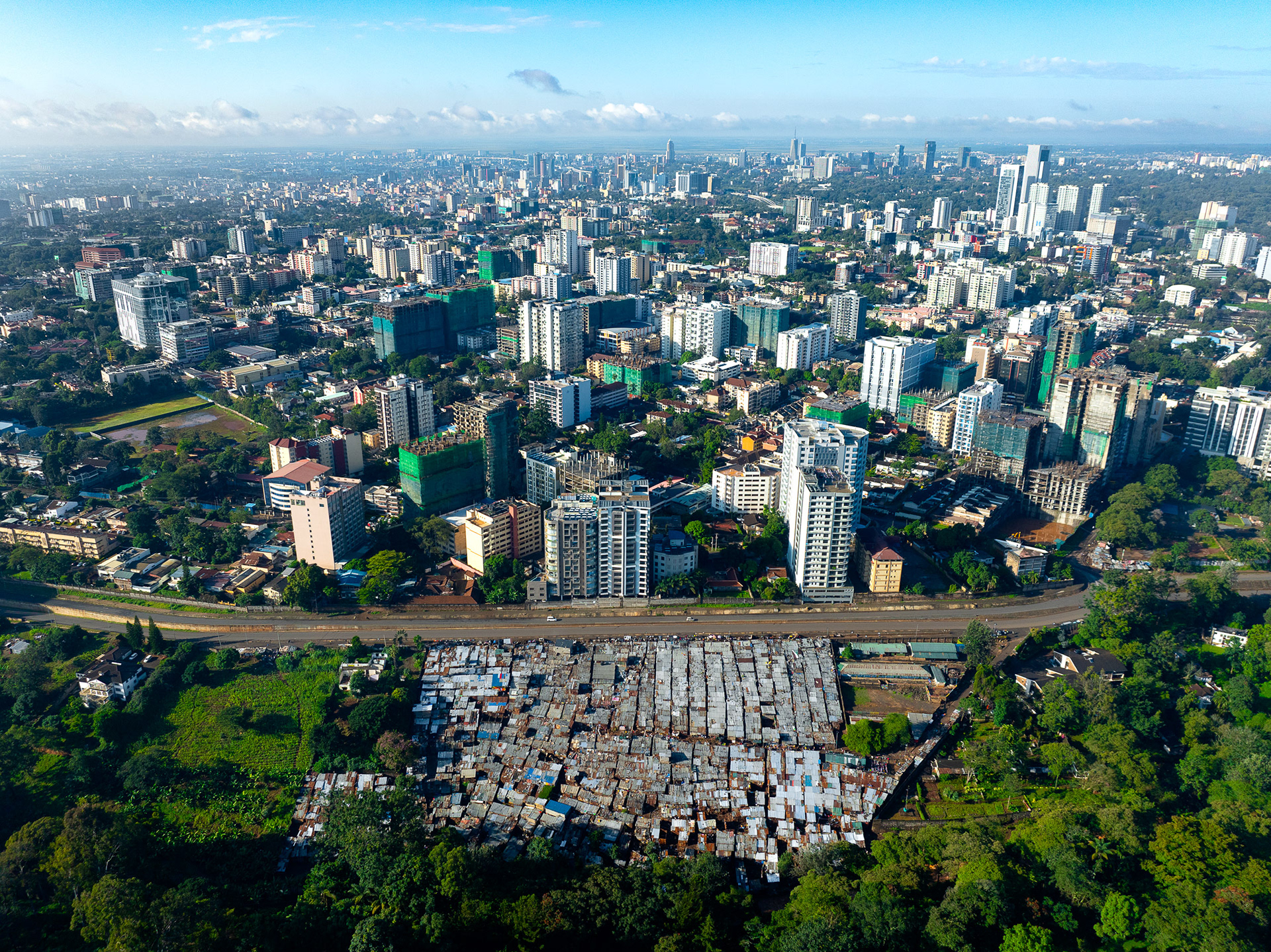 View of Nairobi’s central business district rising behind dense informal settlements in the foreground.