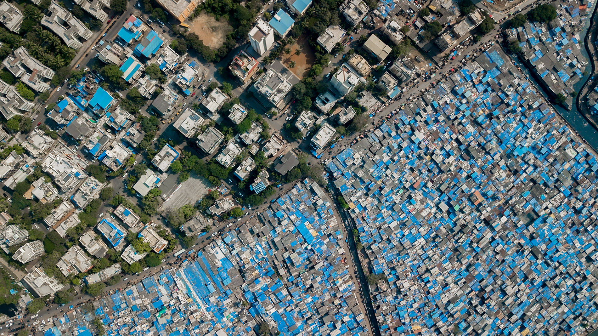 blue tarp slums exist right next to apartment buildings in mumbai india.