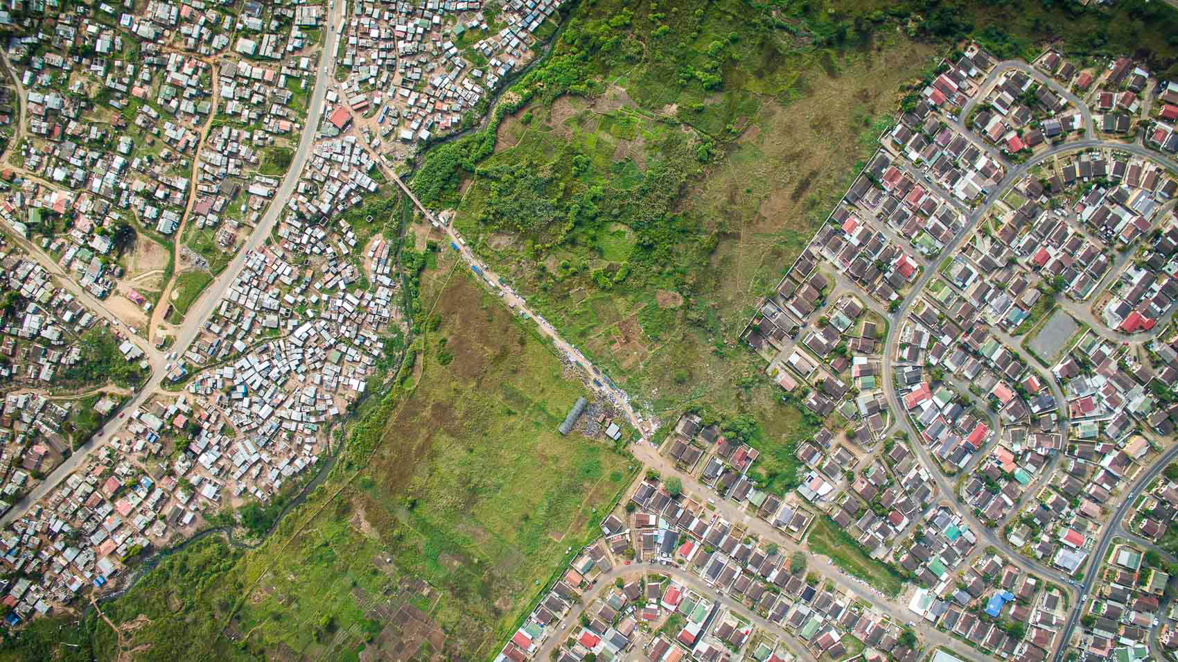 aerial view of shacks and houses with green field in durban