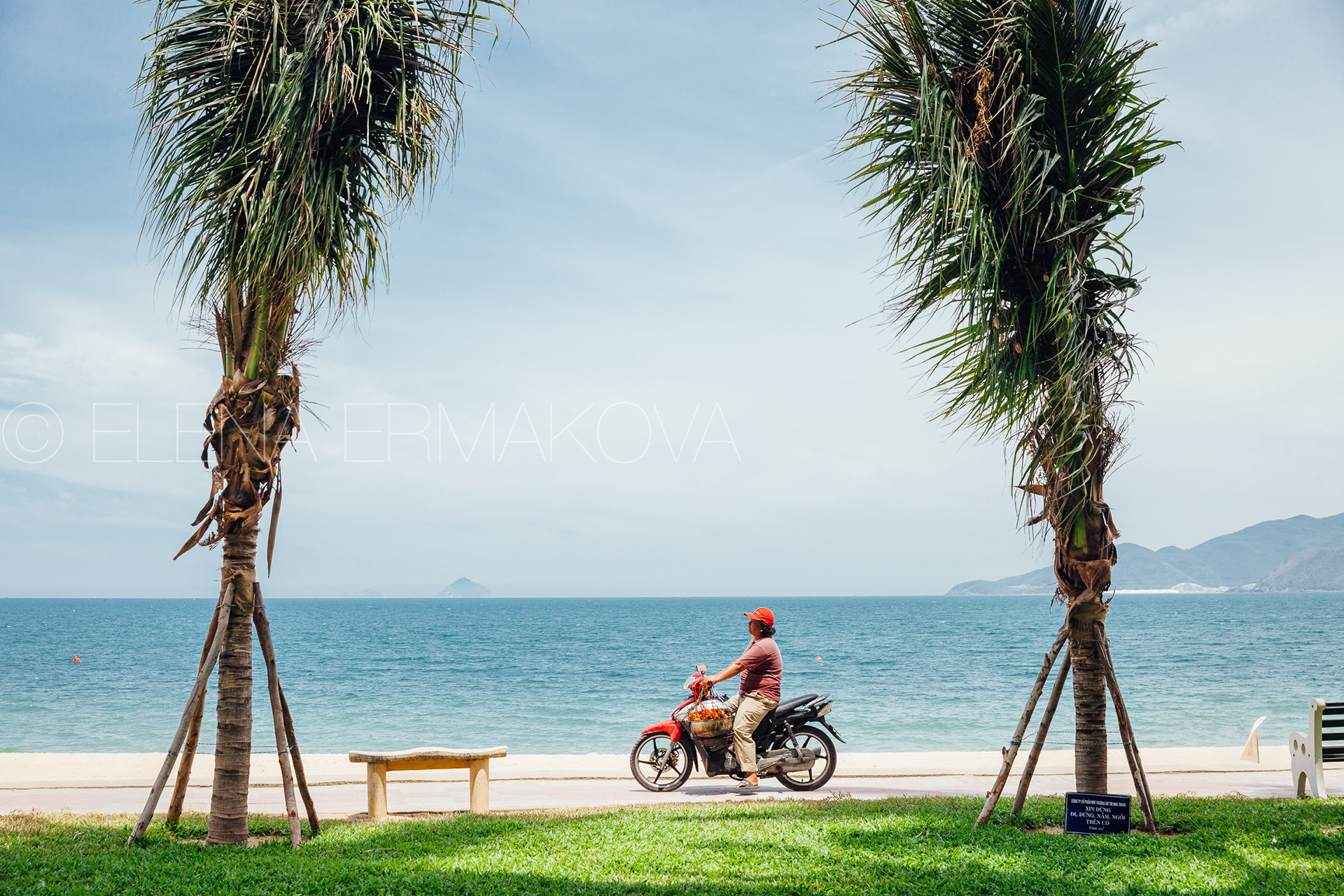 Hard workers on the beach by Elena Ermakova: Beach vendor carries goods for sale along the promenade, September 02, 2018, Nha Trang, Vietnam