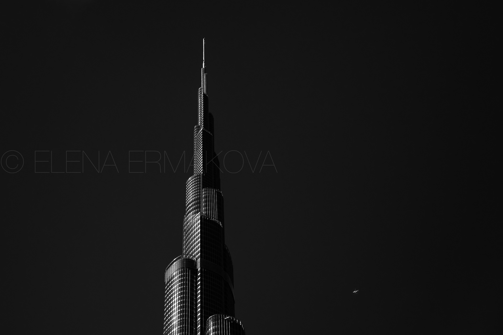 A plane flights over the top of the Burj Khalifa building, Dubai, UAE