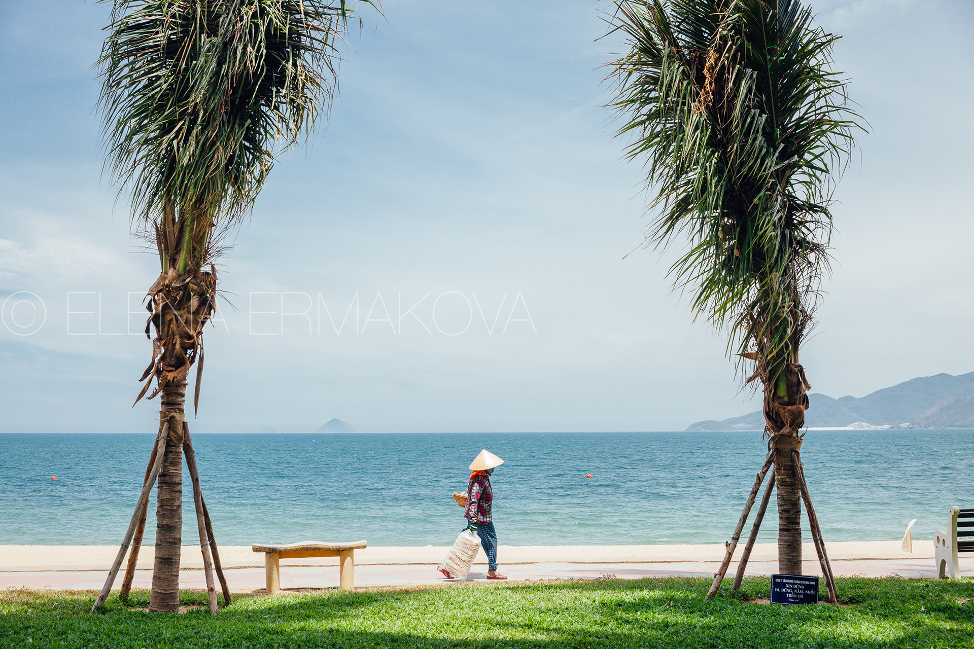Hard workers on the beach by Elena Ermakova: Beach vendor carries goods for sale along the promenade, September 02, 2018, Nha Trang, Vietnam