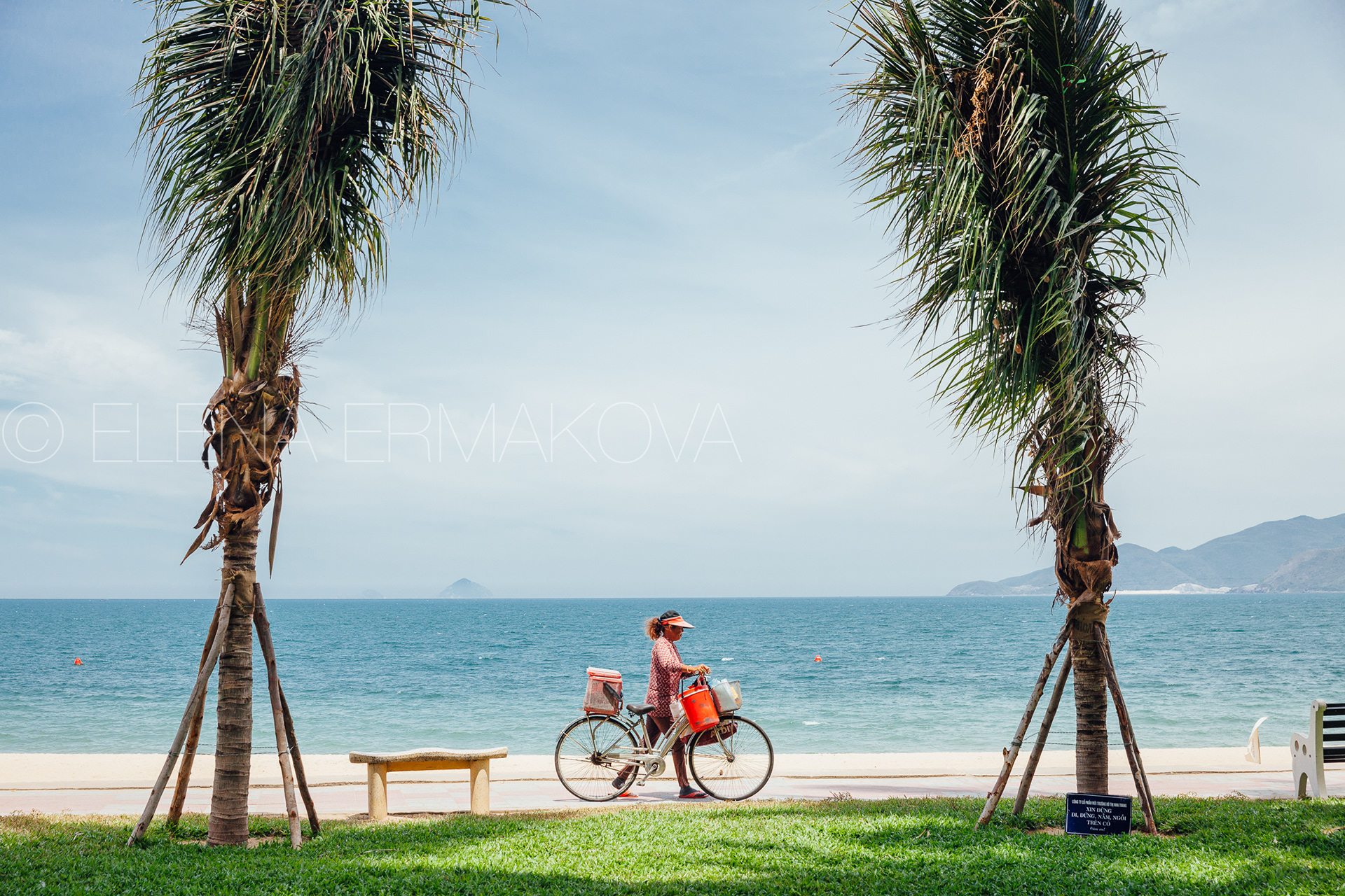 Hard workers on the beach by Elena Ermakova: Beach vendor carries goods for sale along the promenade, September 02, 2018, Nha Trang, Vietnam