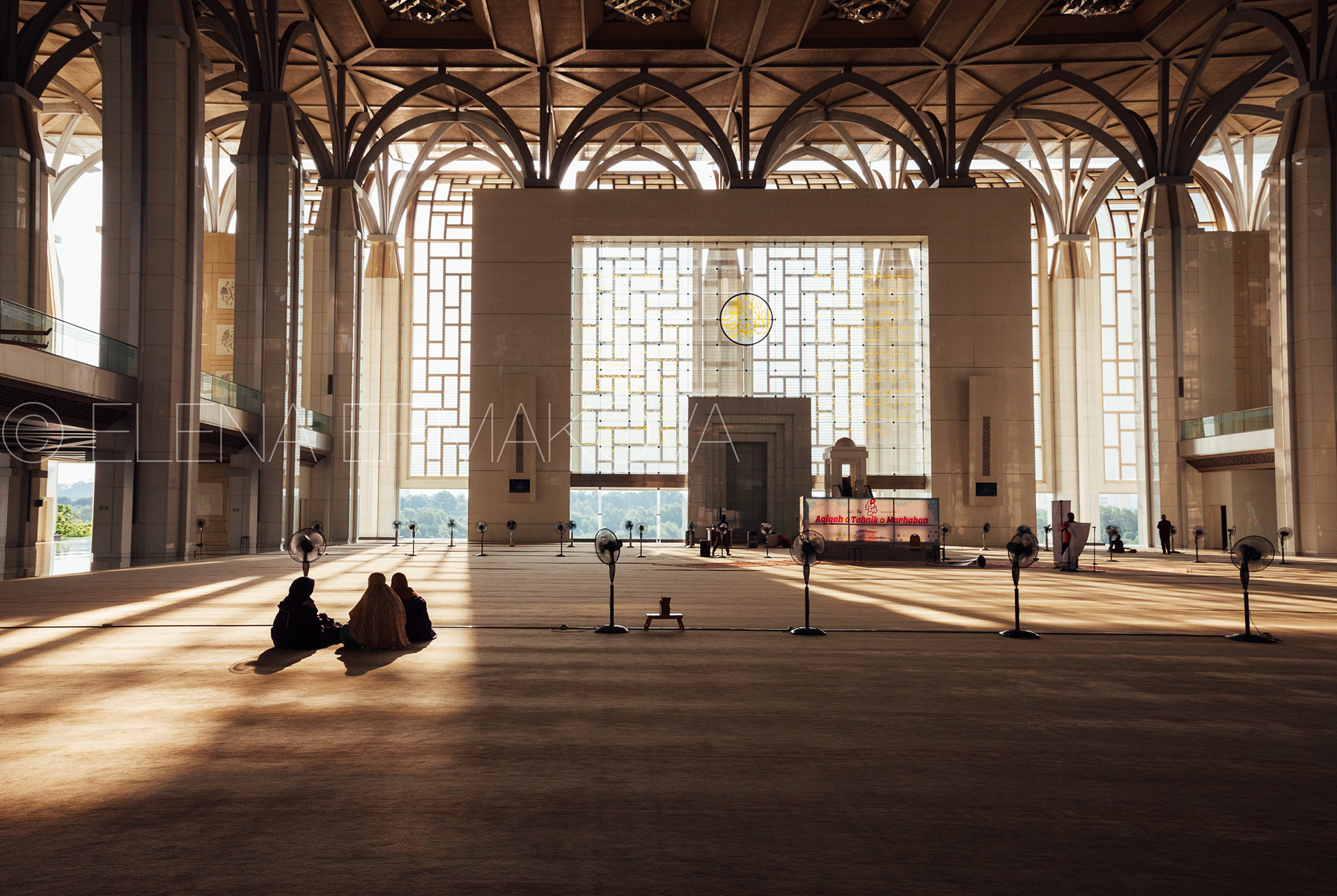 Women sit in the rays of sunset light inside Tuanku Mizan Zainal Abidin Mosque, Putrajaya, Malaysia