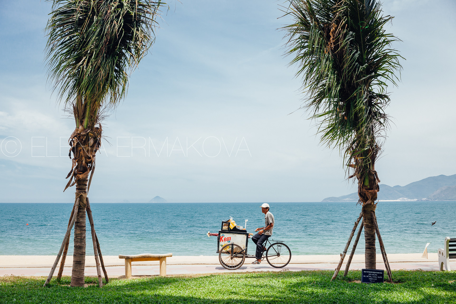Hard workers on the beach by Elena Ermakova: Beach vendor carries goods for sale along the promenade, September 02, 2018, Nha Trang, Vietnam
