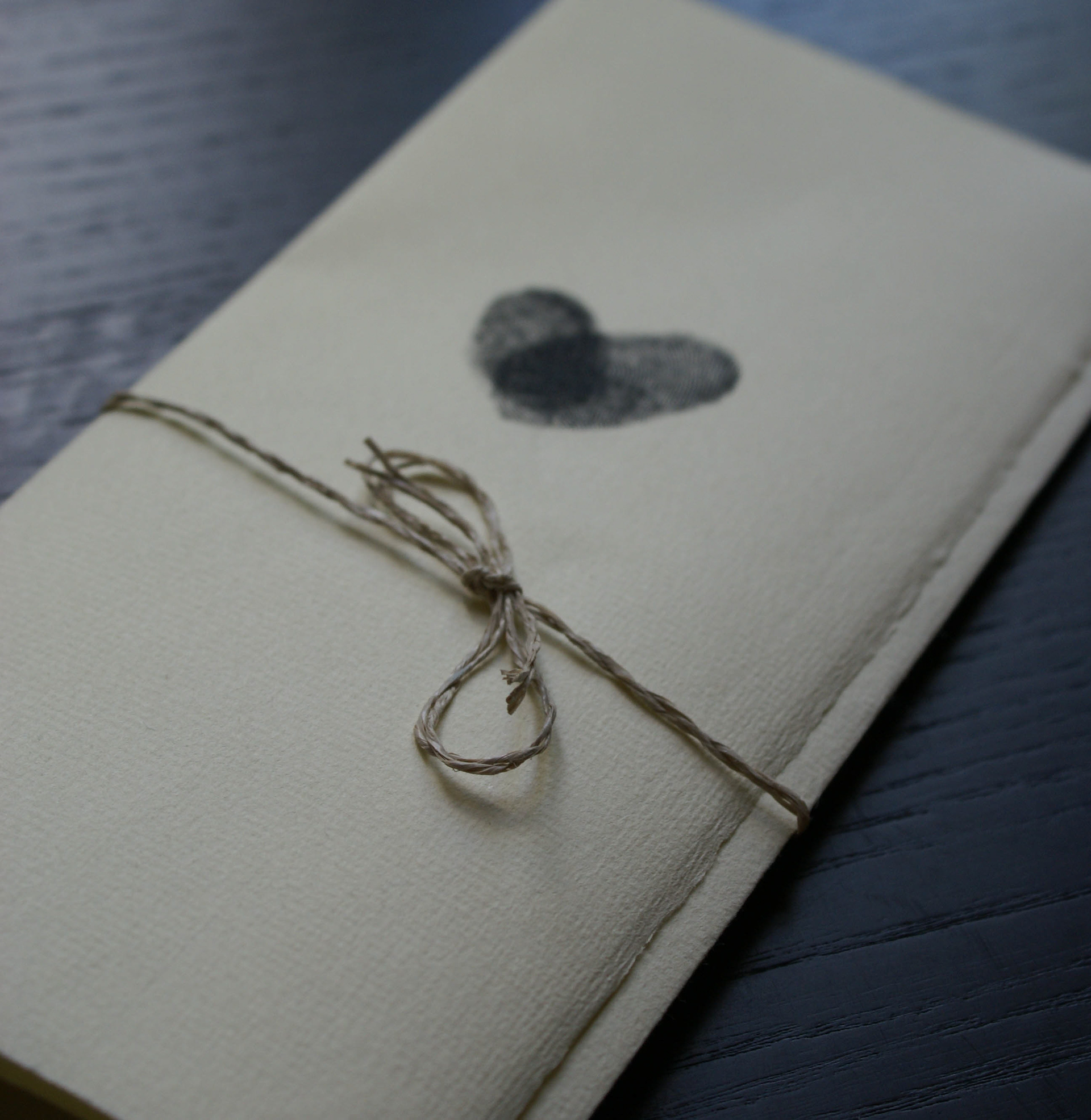 gefaltete Einladung mit persönlichen Fingerabrücken und Papierkordel