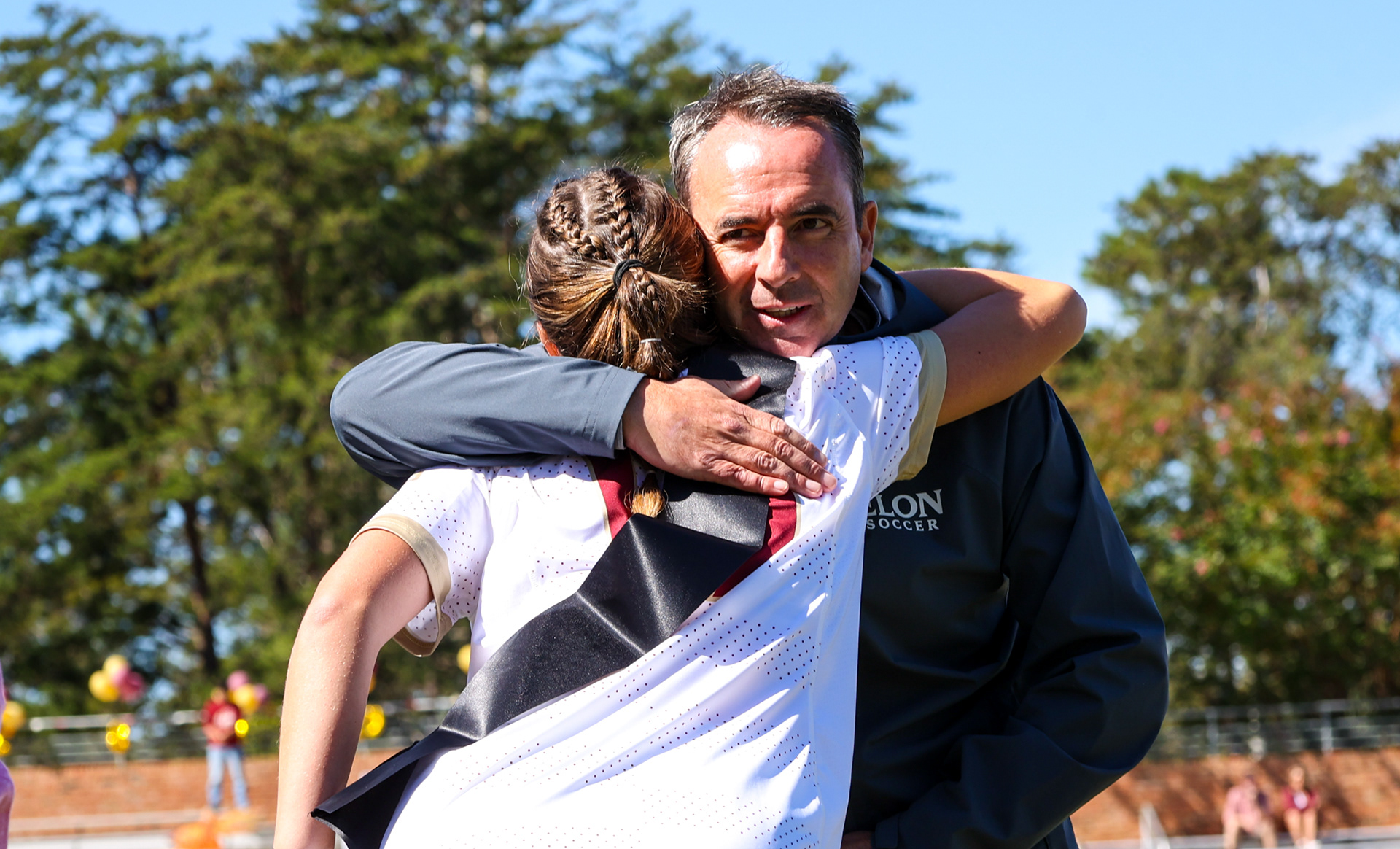 Senior Emilia Cappellett shares a hug with head coach Neil Payne during Elon’s Senior Day ceremony on Oct. 8, 2023. Photo by Jacob Kisamore.