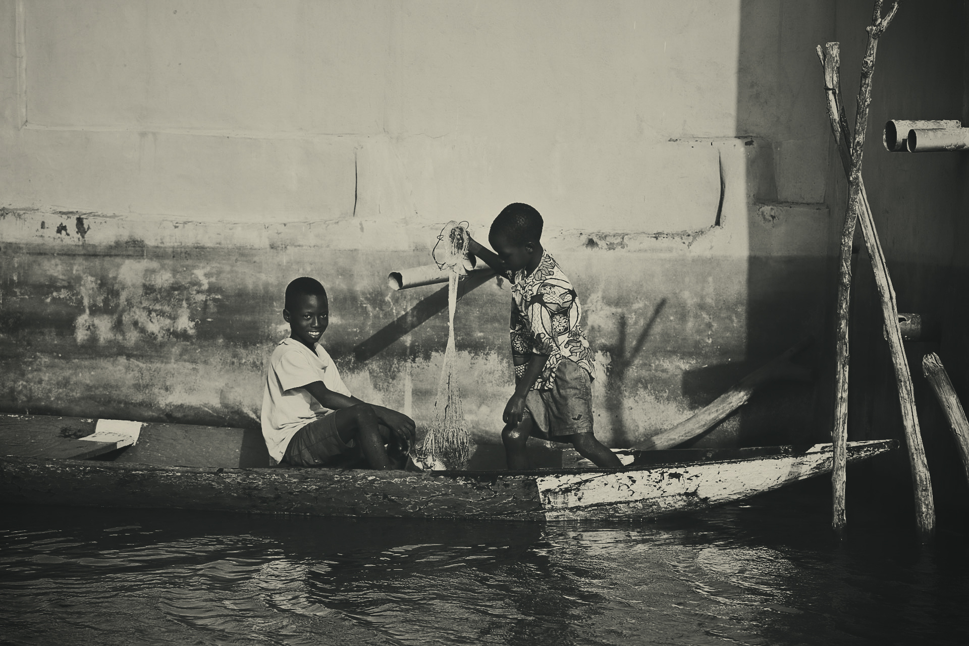 Two children from Ganvié prepare for fishing from their traditional boat, perpetuating the ancestral art of family subsistence - Benin 2018
