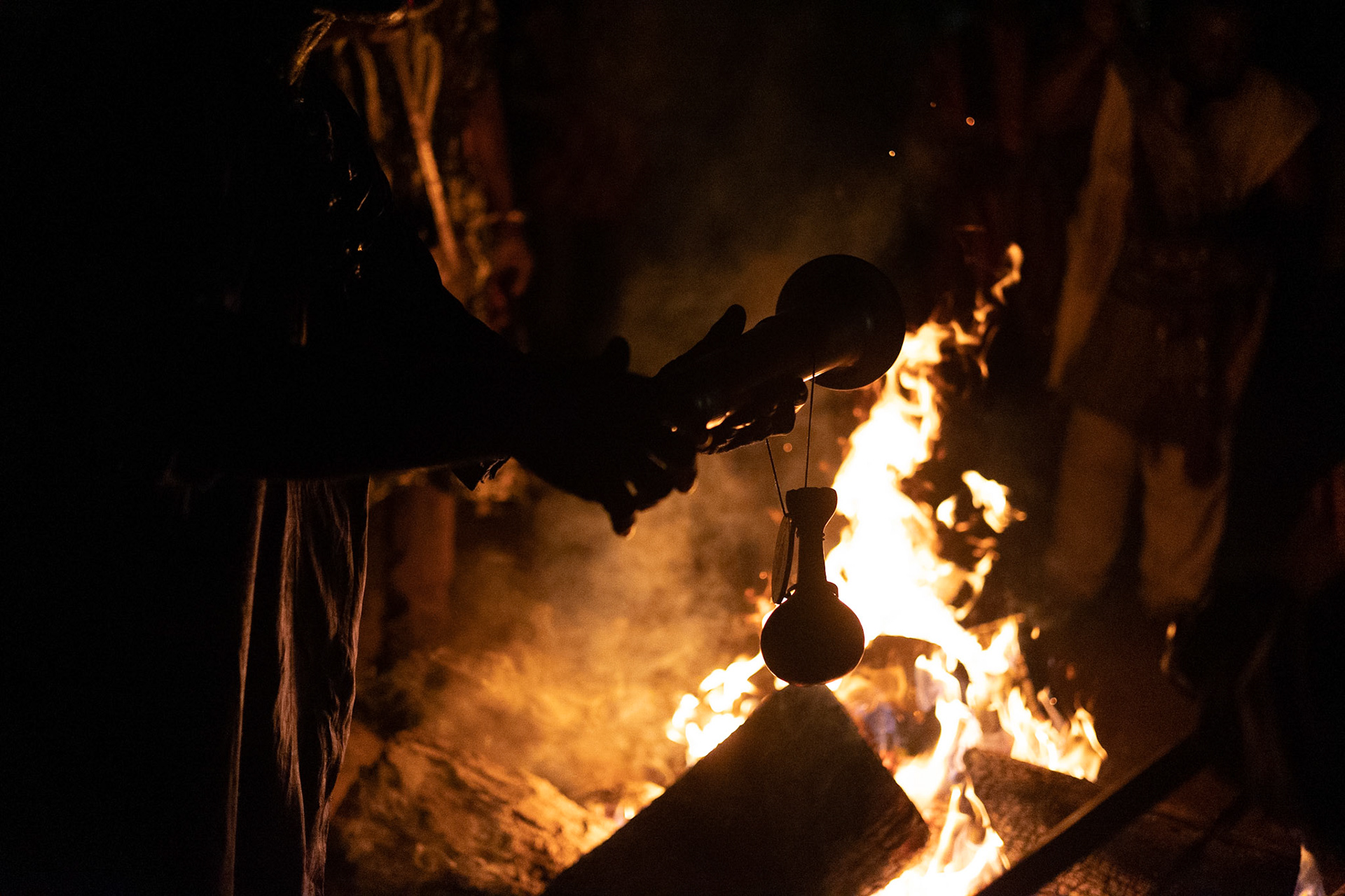 Kana - Cultural Ceremony man singing and dancing with traditional sword ritual, Cameroon 2022 - Man holding an instrument in front of fire.