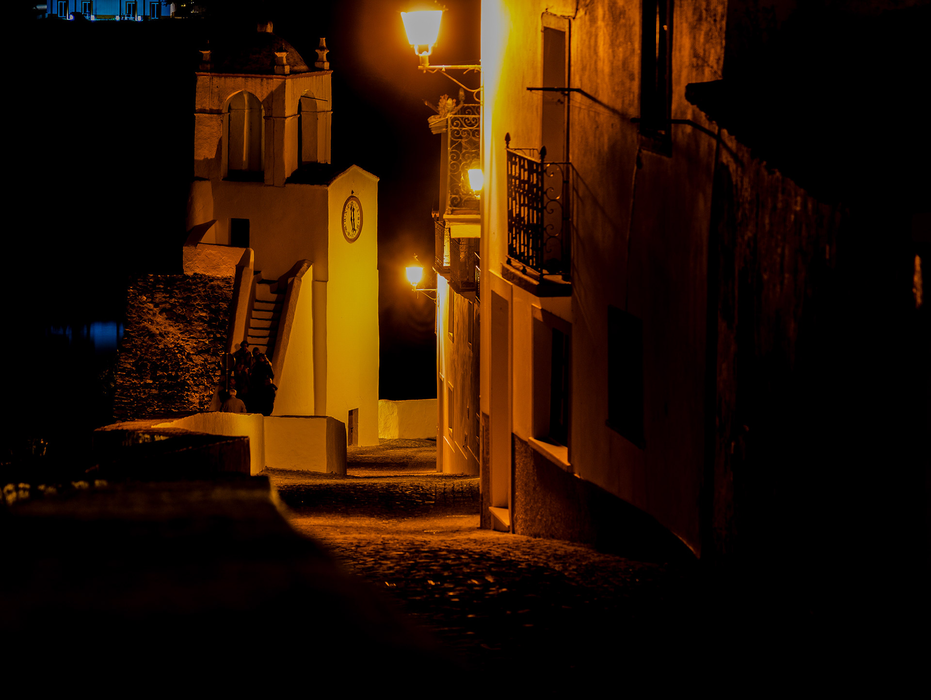 Calm landscape of Mértola with soft light over the river and surrounding hills under a clear sky.
