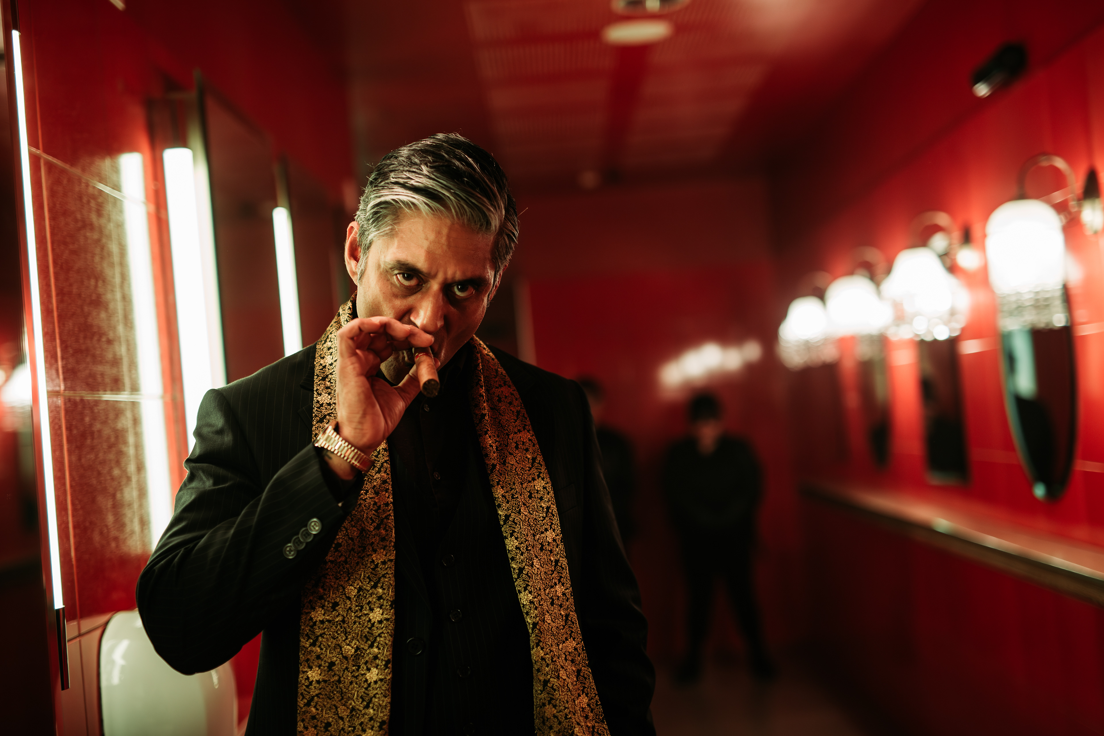 Mel Odedra as Toby "The King" taking a puff of his cigar, photo by Ankita Singh 2023