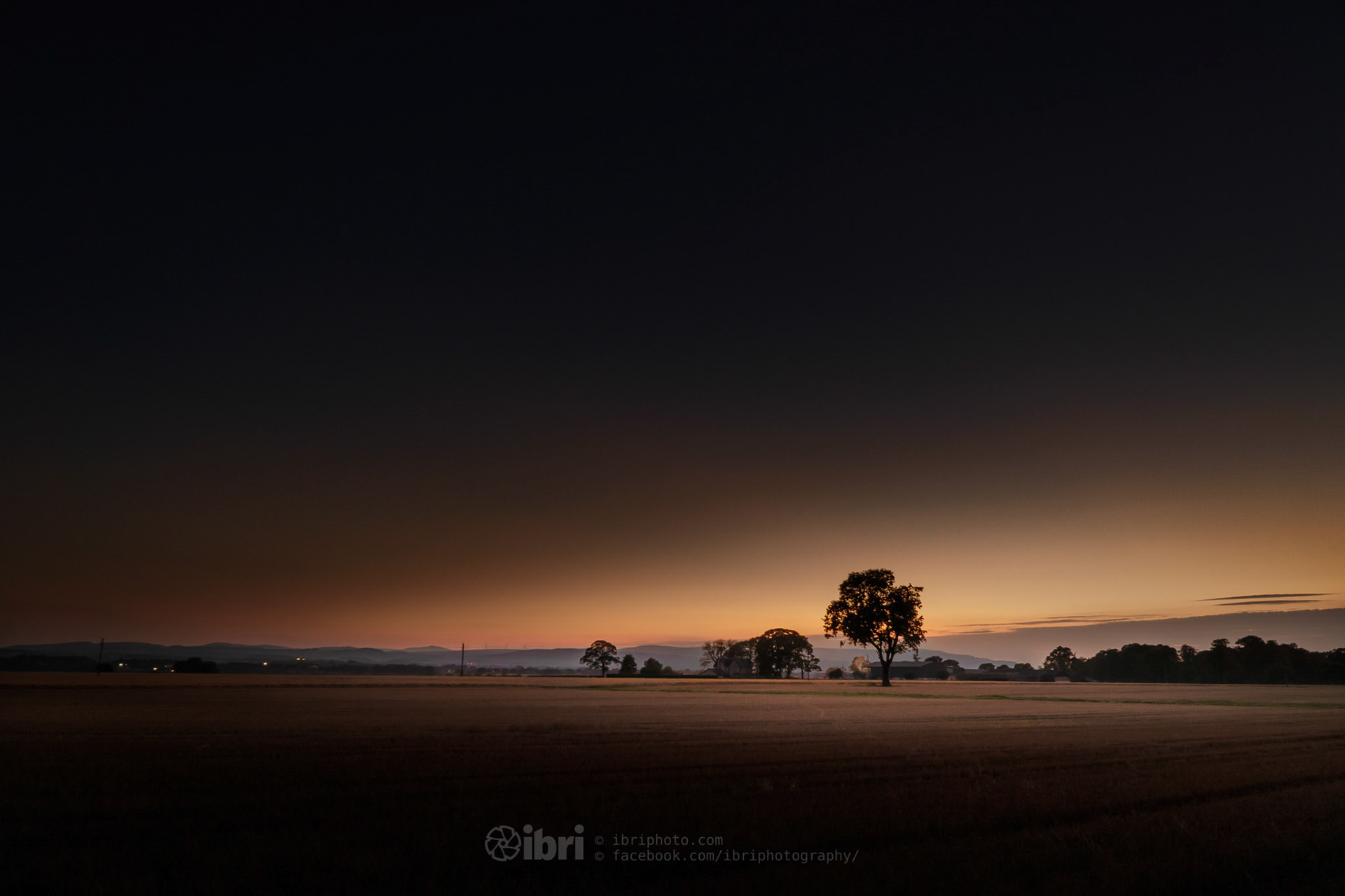The dying embers of a September sunset over a field and farm buidings